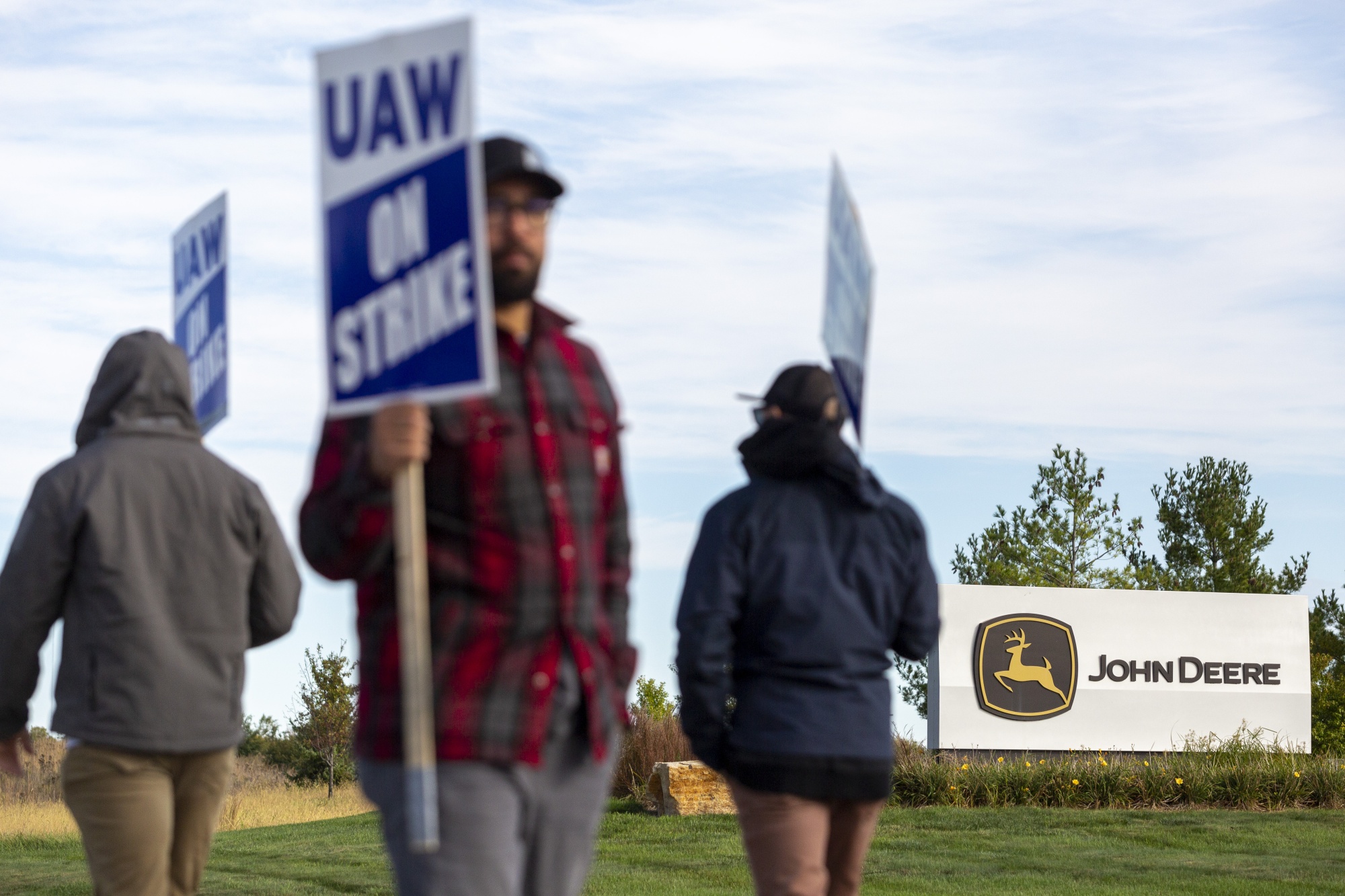 Workers hold signs during a strike outside the John Deere Des Moines Works facility in Ankeny, Iowa, on Oct. 15.