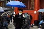 Visitors wearing face masks walk along a shopping street leading to the Sensoji temple in the Asakusa district of Tokyo.