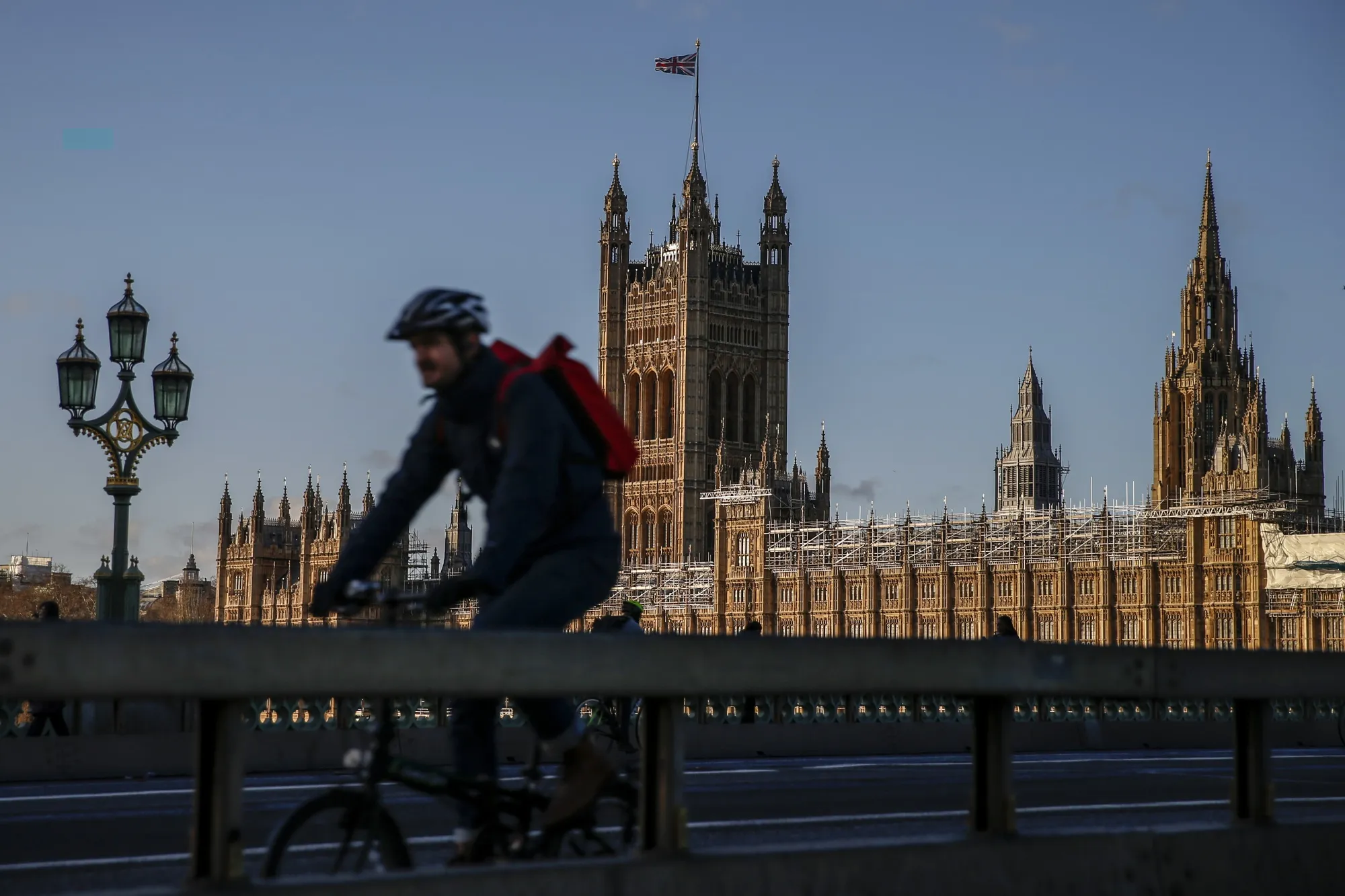 A cyclist crosses Westminster Bridge in view of the Houses of Parliament in London.