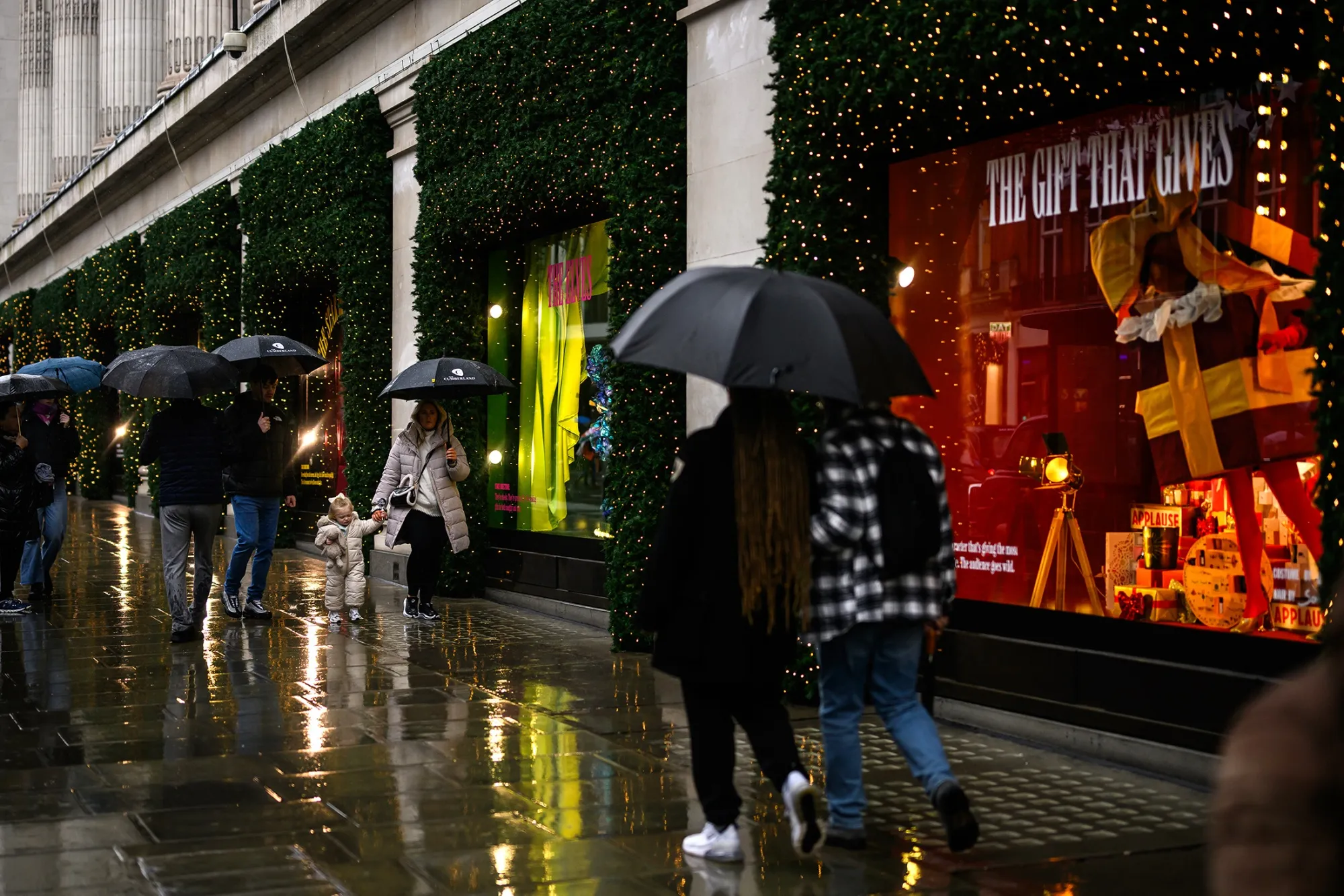 Shoppers shelter from rain as they walk along Oxford Street in London on Dec. 19. 
