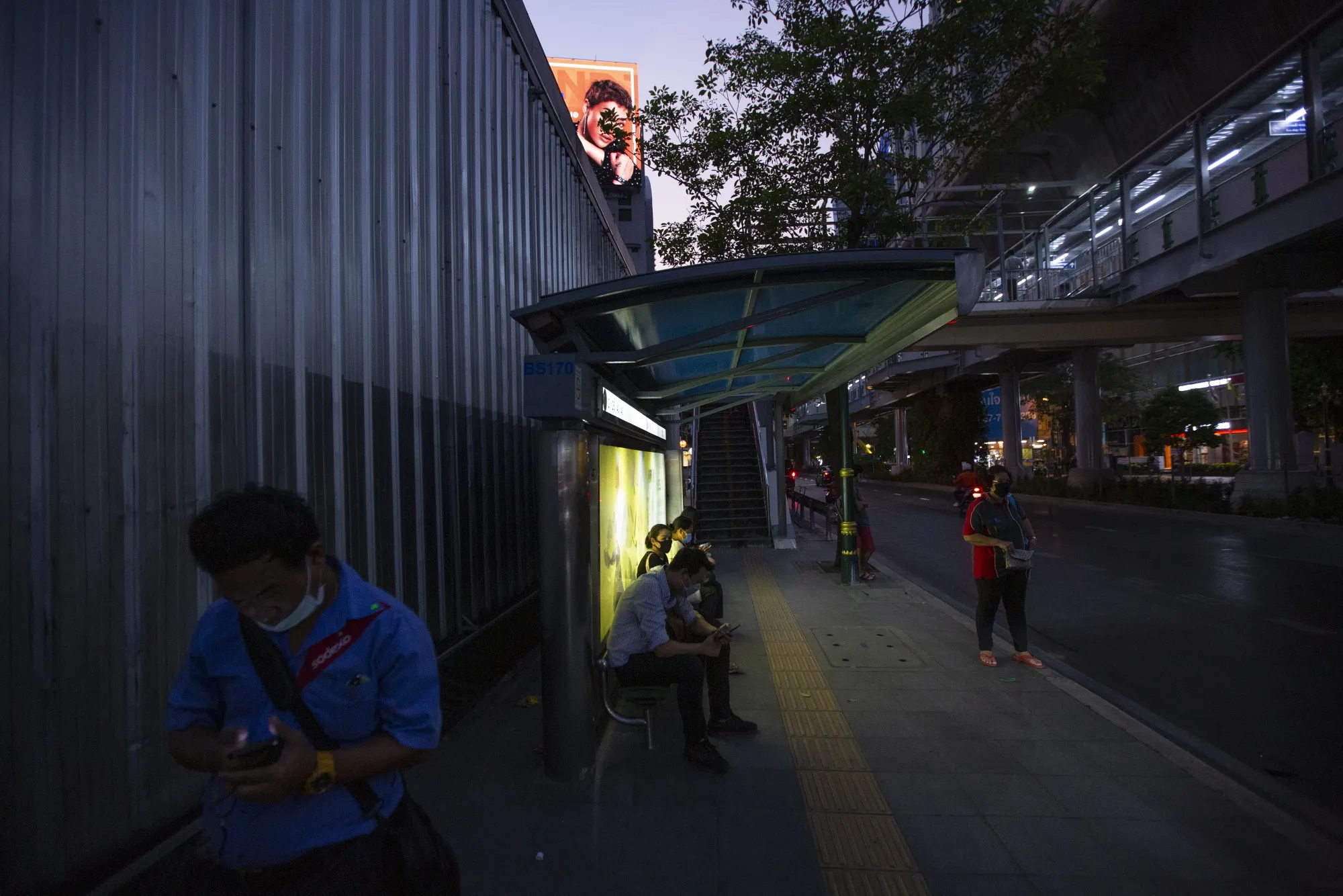 People wait at a bus stop&nbsp;in Bangkok.