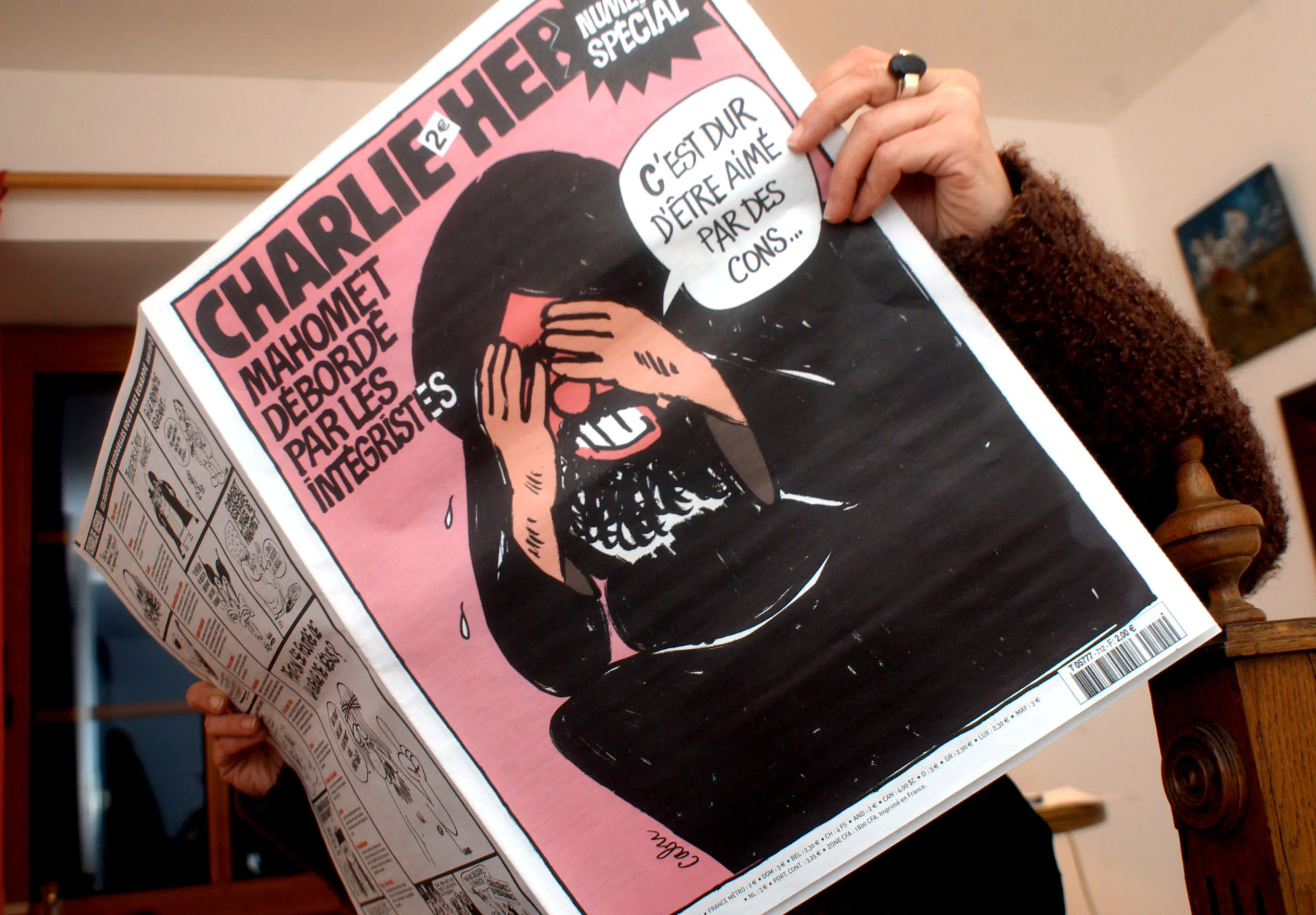 A woman displays an issue of Charlie Hebdo magazine for this photograph in Belleme, France Wednesday, February 8, 2006.
