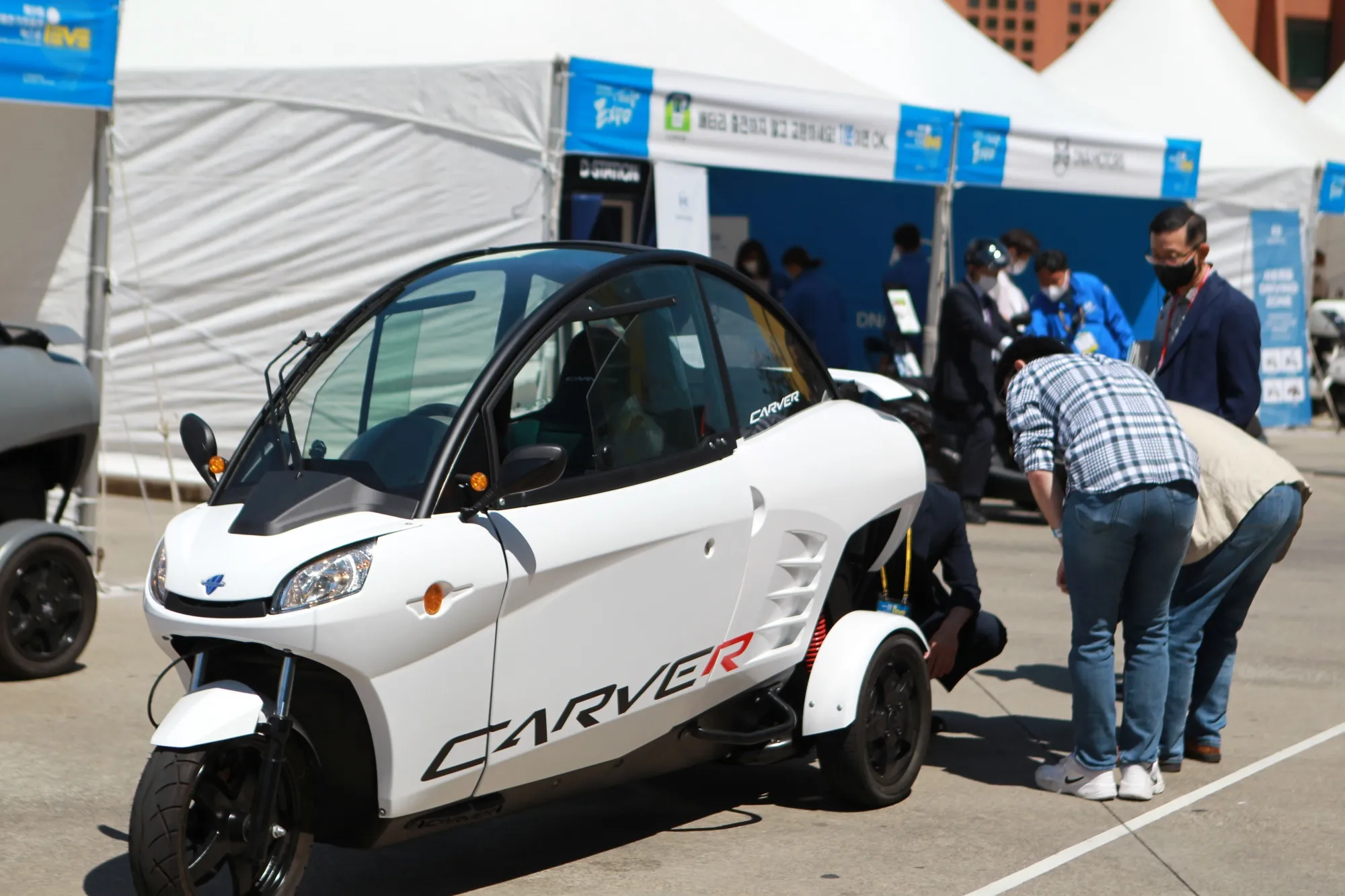 Attendees look at a three-wheeler Carver.
