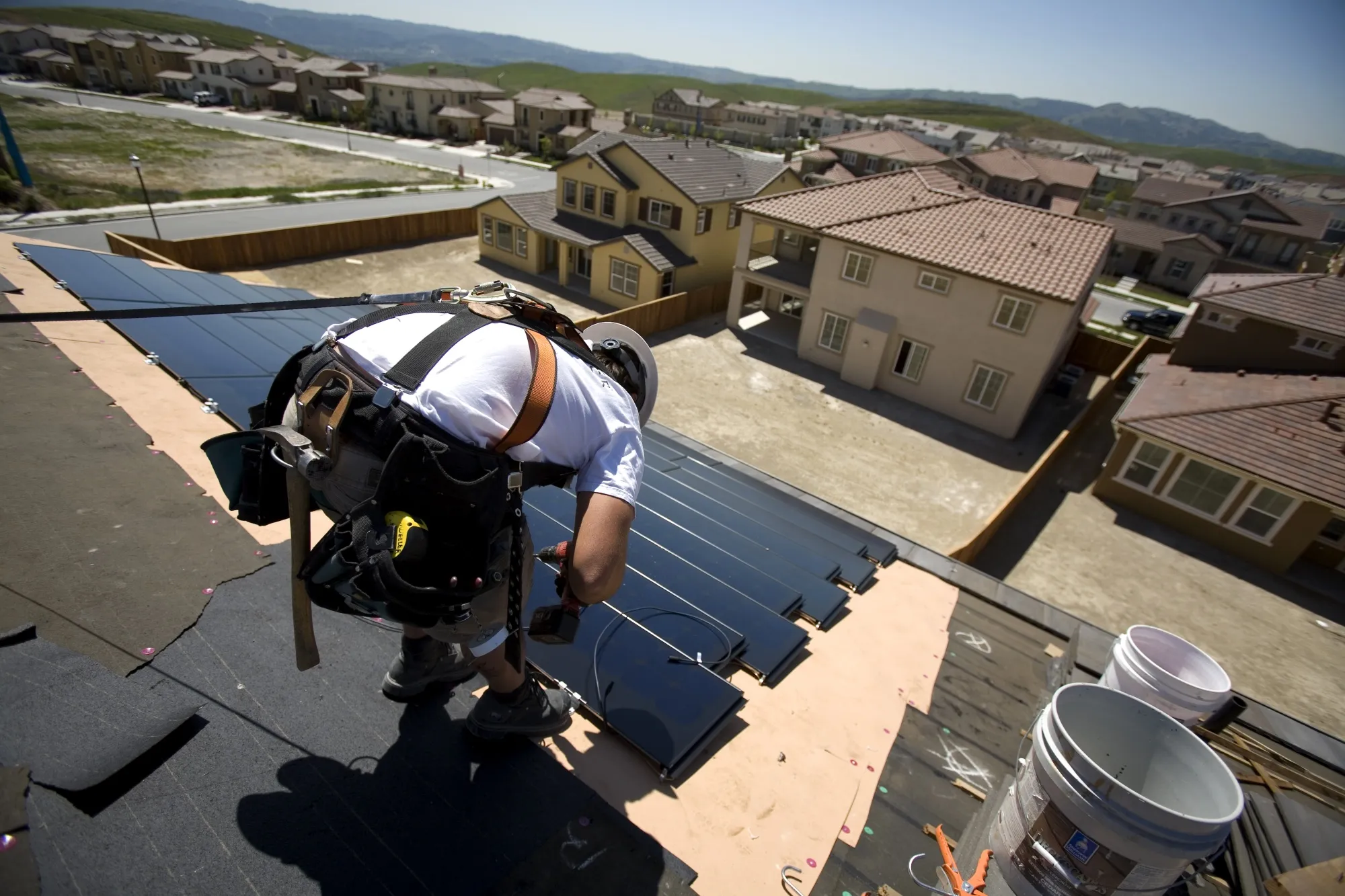 Construction workers from SunPower Corporation install a&nbsp;rooftop solar panel array on new homes.