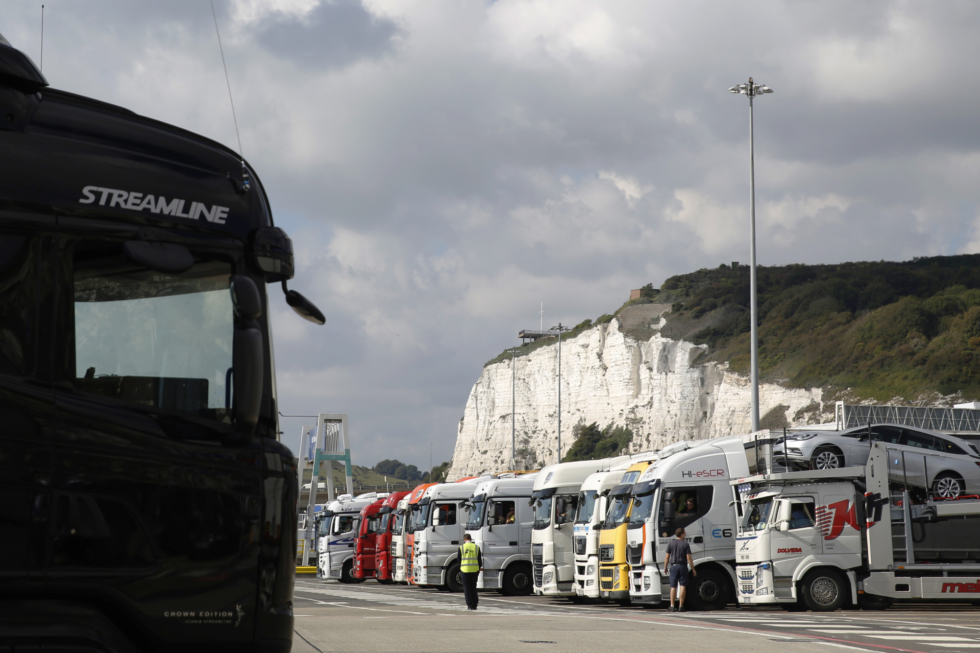 A cargo truck disembarks a cross channel ferry while others wait to board at the Port of Dover.