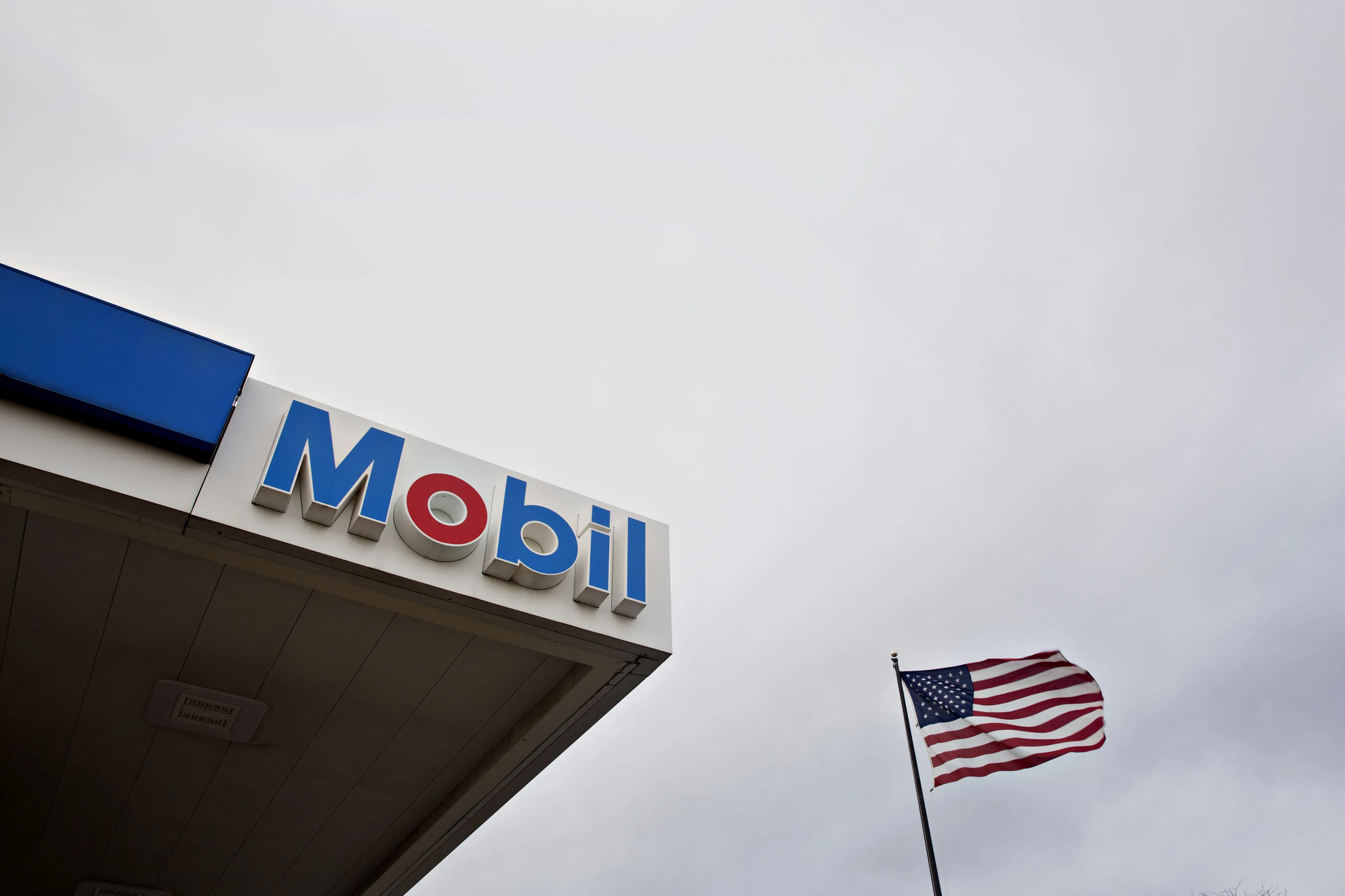 An American flag flies next to an Exxon Mobil Corp. gas station in Cherry Valley, Illinois.&nbsp;