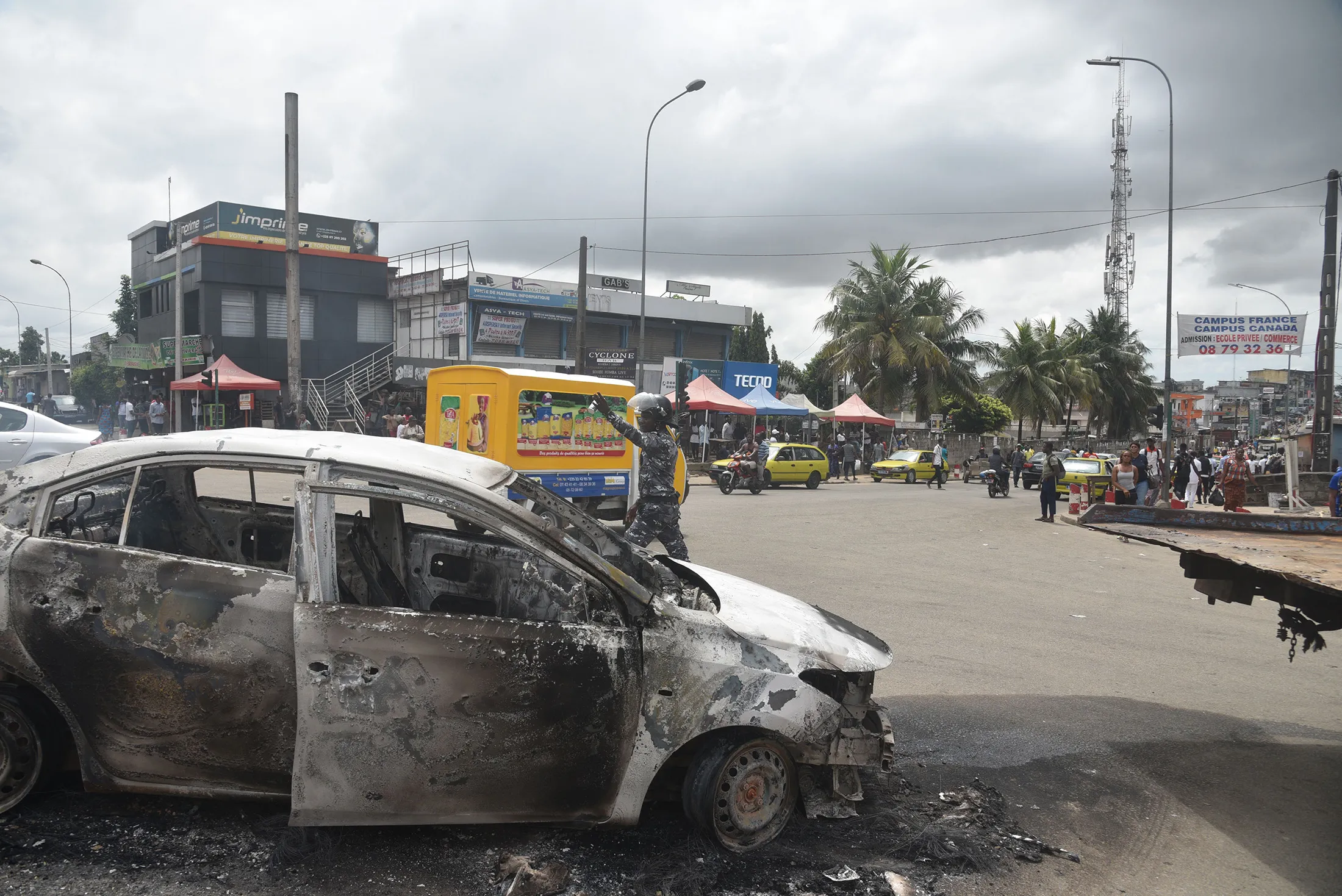 An Ivorian police officer gestures next to a burnt car&nbsp;during demonstrations against a third term of the outgoing Ivorian President Alassane Ouattara in&nbsp;Abidjan on Oct.&nbsp;19.