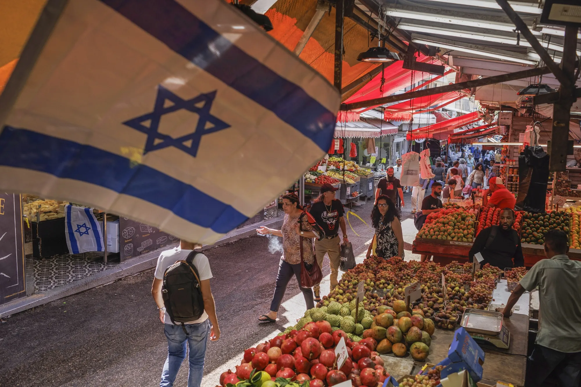 An Israeli national flag above produce for sale at Carmel Market in Tel Aviv.