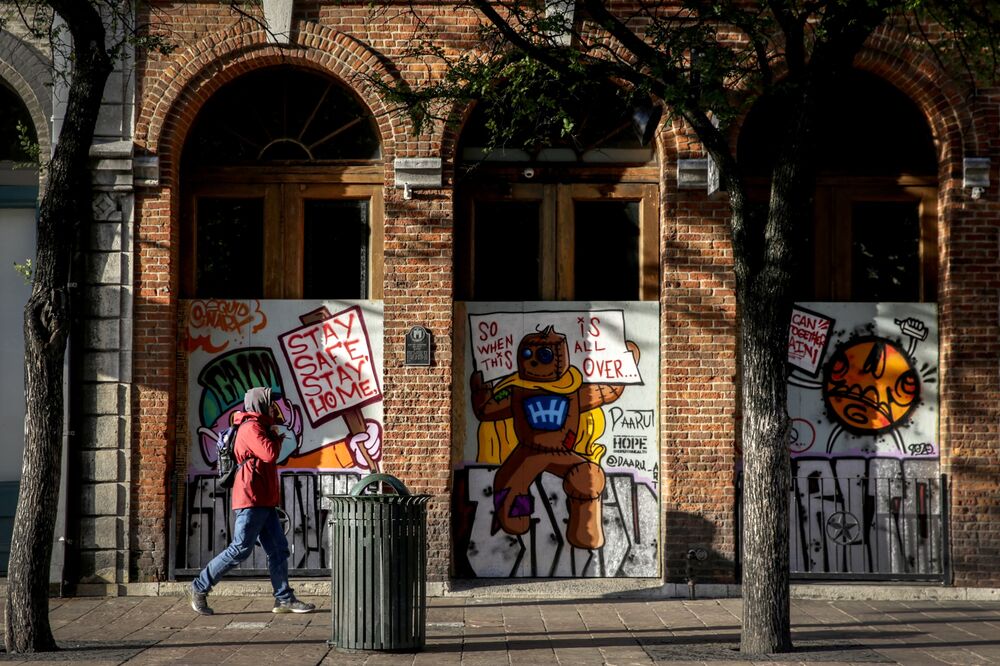 A pedestrian passes in front of a boarded up business on East Sixth Street in downtown Austin, Texas on April 13.