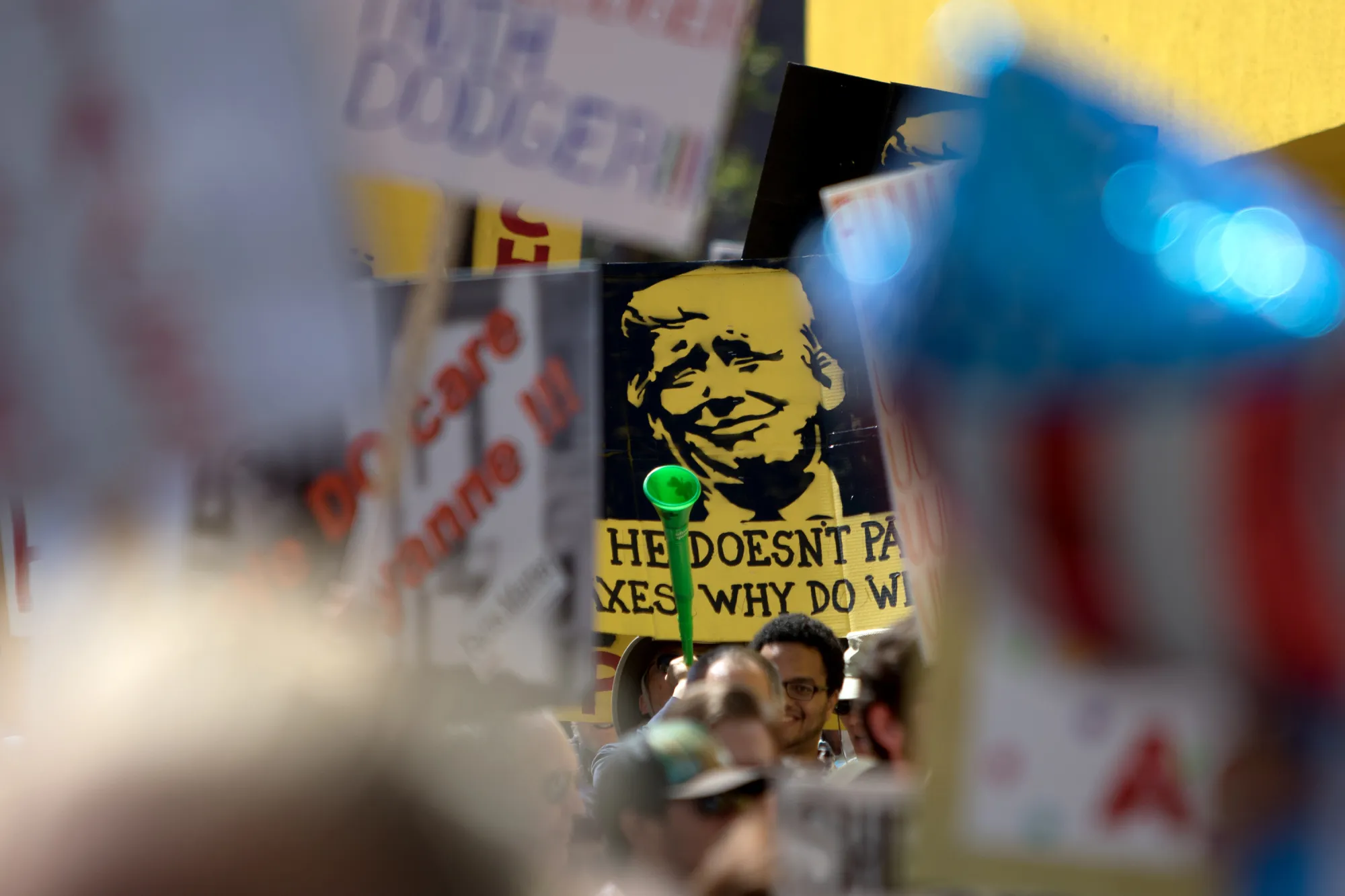 Demonstrators gather and hold signs before the start of the Tax March Los Angeles on April 15, 2017.