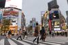 Pedestrians walk across a road in the Shibuya district of Tokyo, Japan.