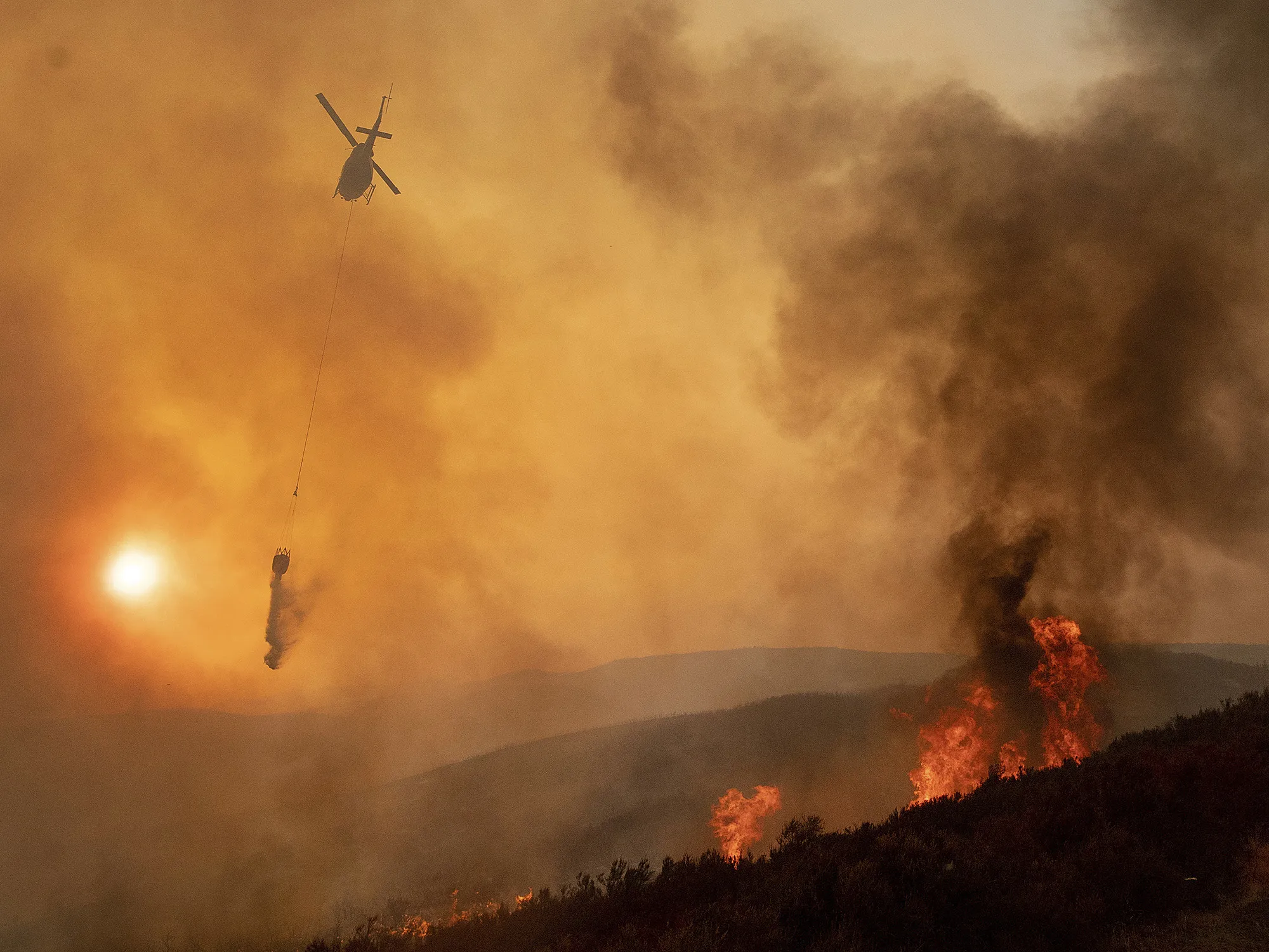 A helicopter drops water on a burning hillside during the Ranch Fire in Clearlake Oaks, California on Aug. 5.