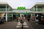 A customer pushes a shopping cart as she walks towards an Asda supermarket, operated by Wal-Mart Stores Inc., in the Wembley district of London, U.K.