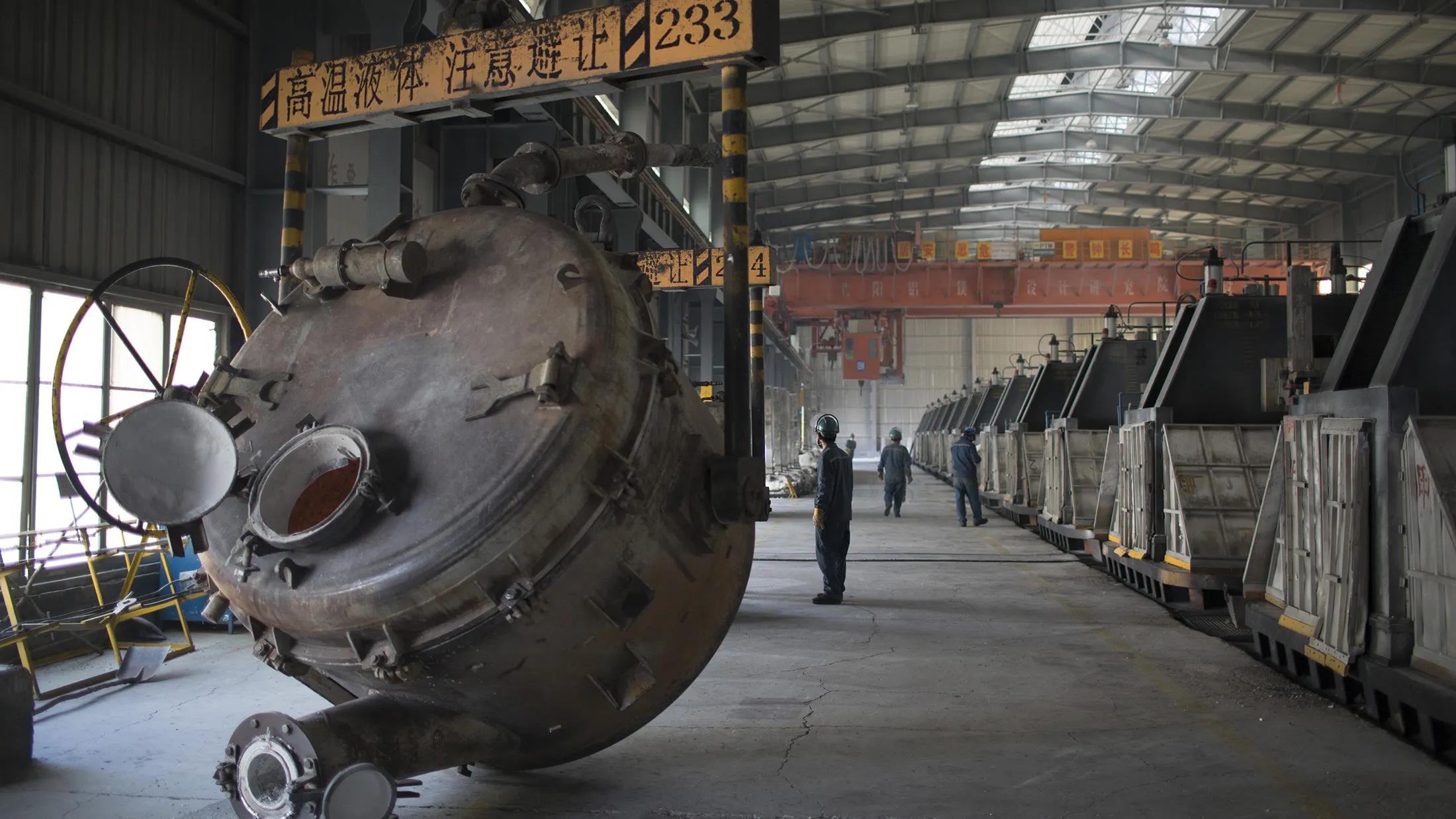 Employees walk through the aluminum smelting room at the China Hongqiao Group Ltd. aluminum smelting facility in Zouping, China, on Monday, Nov. 4, 2013. China Hongqiao Group is China's largest private aluminum maker.
