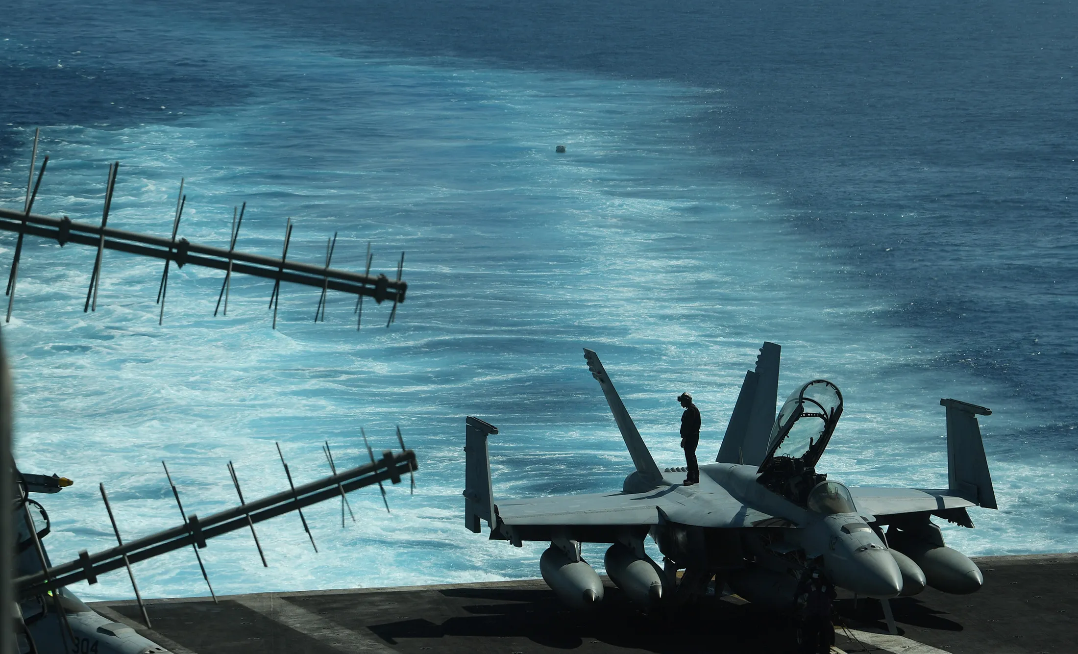 A sailor stands atop an FA-18 hornet fighter jet during a routine training aboard US aircraft carrier Theodore Roosevelt in the South China sea in 2018.