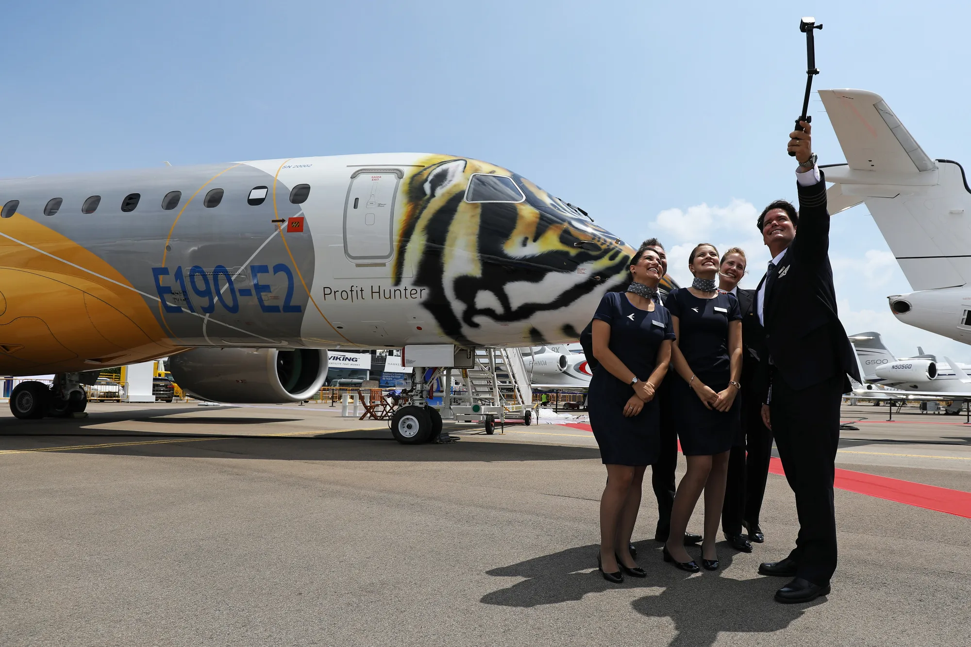 Flight attendants take a selfie&nbsp;in front of a prototype of the Embraer SA E-190 E2 passenger aircraft.