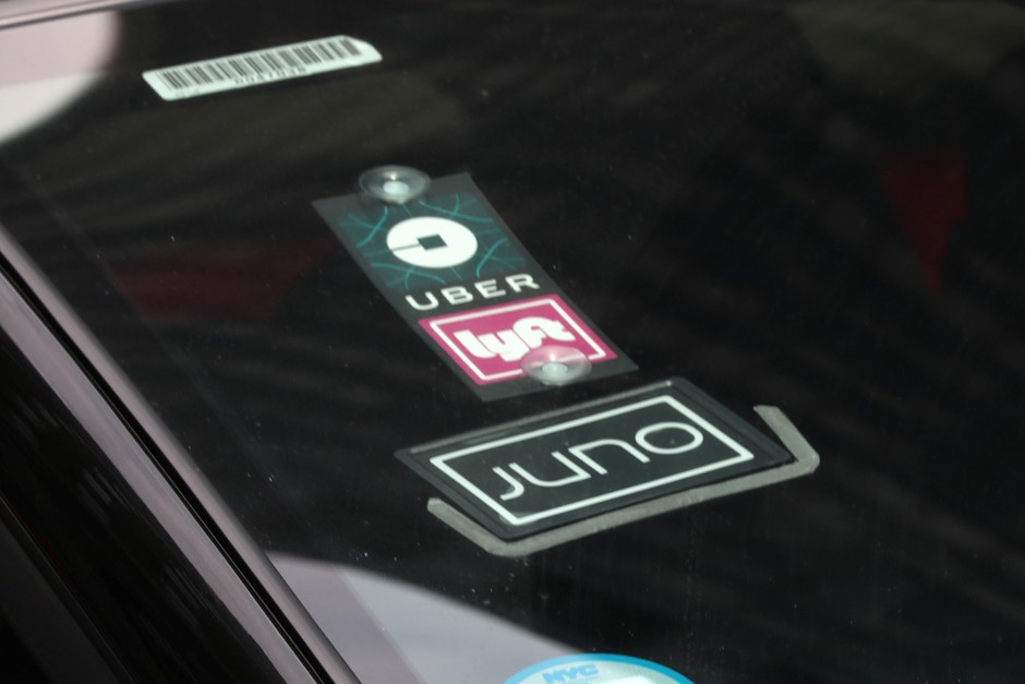 A New York City car displays logos for three ride-hire services. While a number of transport gig workers drive for several different services, a new study finds that participation is often short-lived.