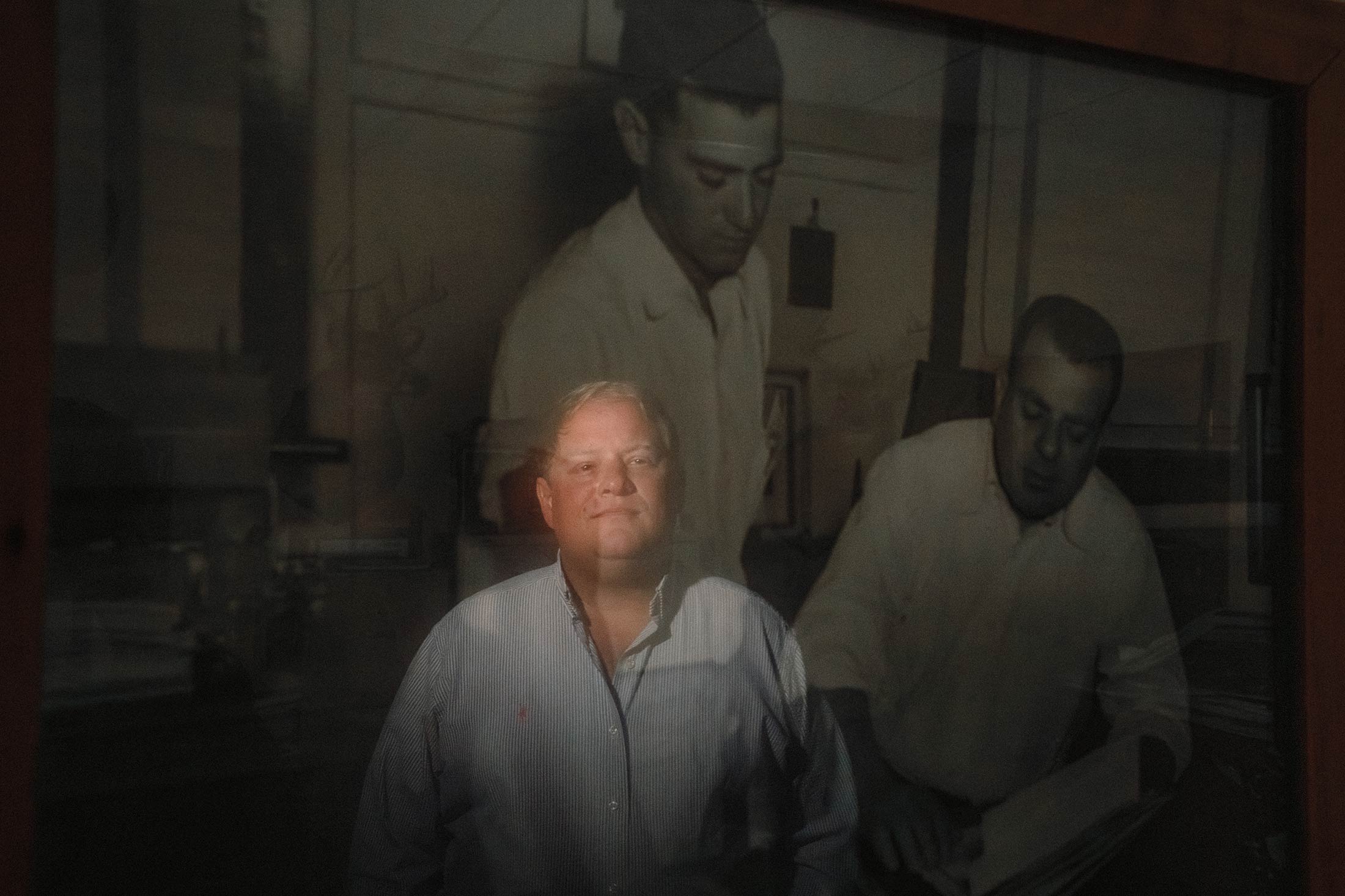 A portrait of Scott Franklin, in front of a photo of his grandfather and great-grandfather.