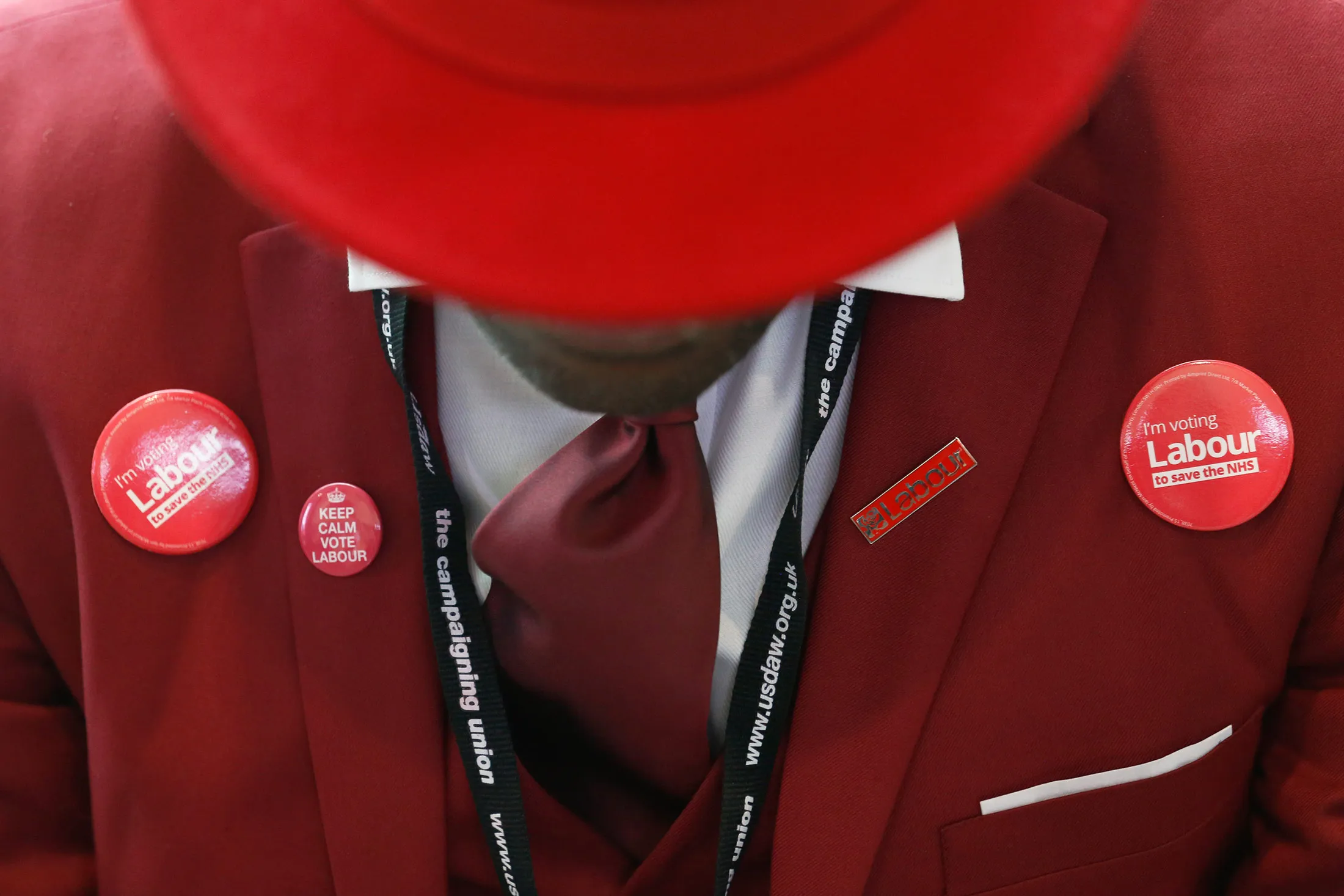 An attendee, wearing a red suit and a red hat, wears badges emblazoned with the Labour logo at the annual conference of the U.K. opposition Labour Party in Liverpool, U.K., on Wednesday, Sept. 28, 2016. Jeremy Corbyn, leader of the Labour Party, will order his rebellious lawmakers to fall into line behind him and prepare for a general election he’ll say he expects Prime Minister Theresa May to call next year.
