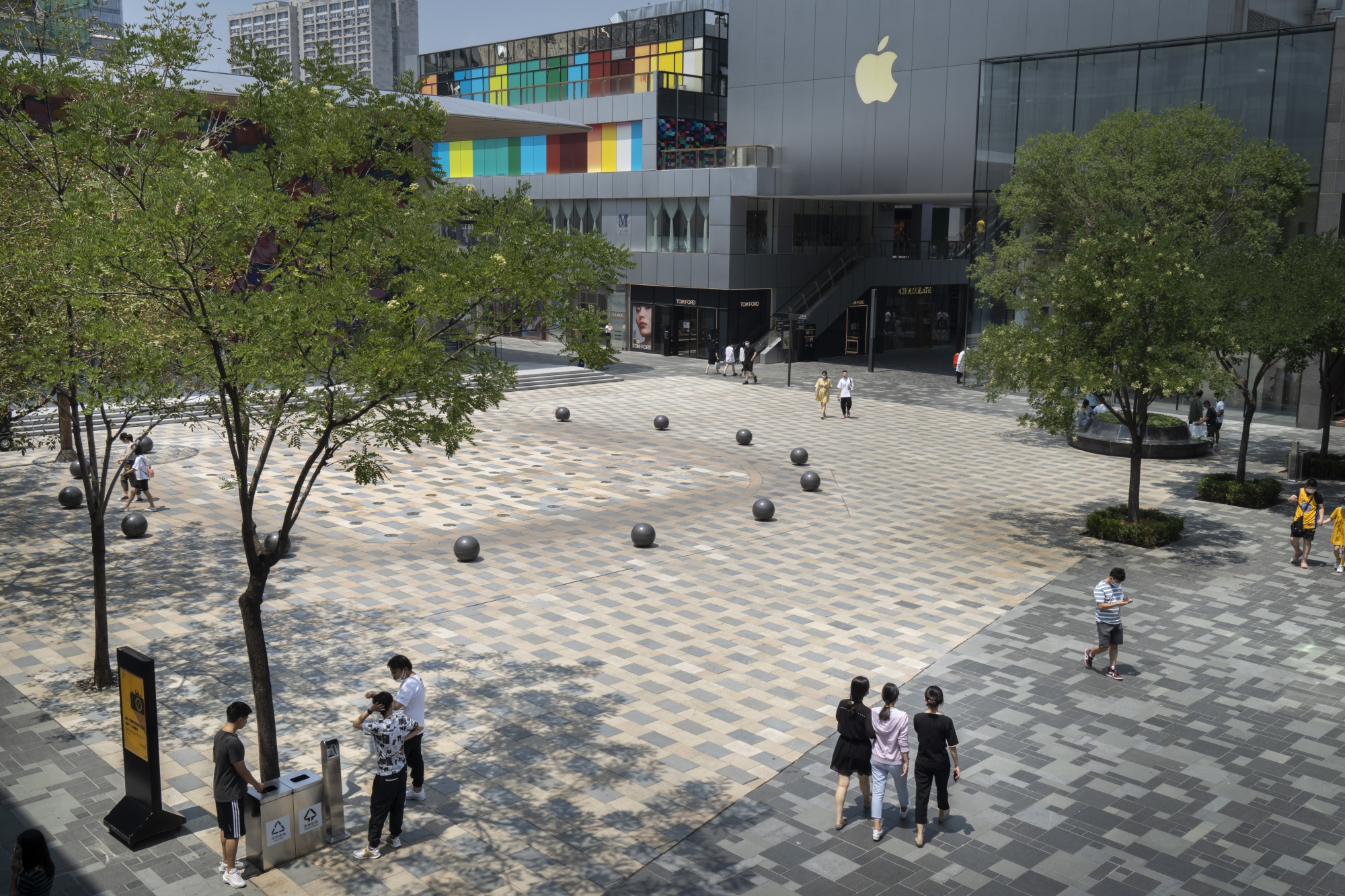 Pedestrians walk through a plaza in front of an Apple Inc. store in the Sanlitun area in Beijing on July 15.