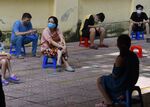 Residents wearing face masks wait to get tested at a temporary testing centre in Hanoi on Aug. 8.