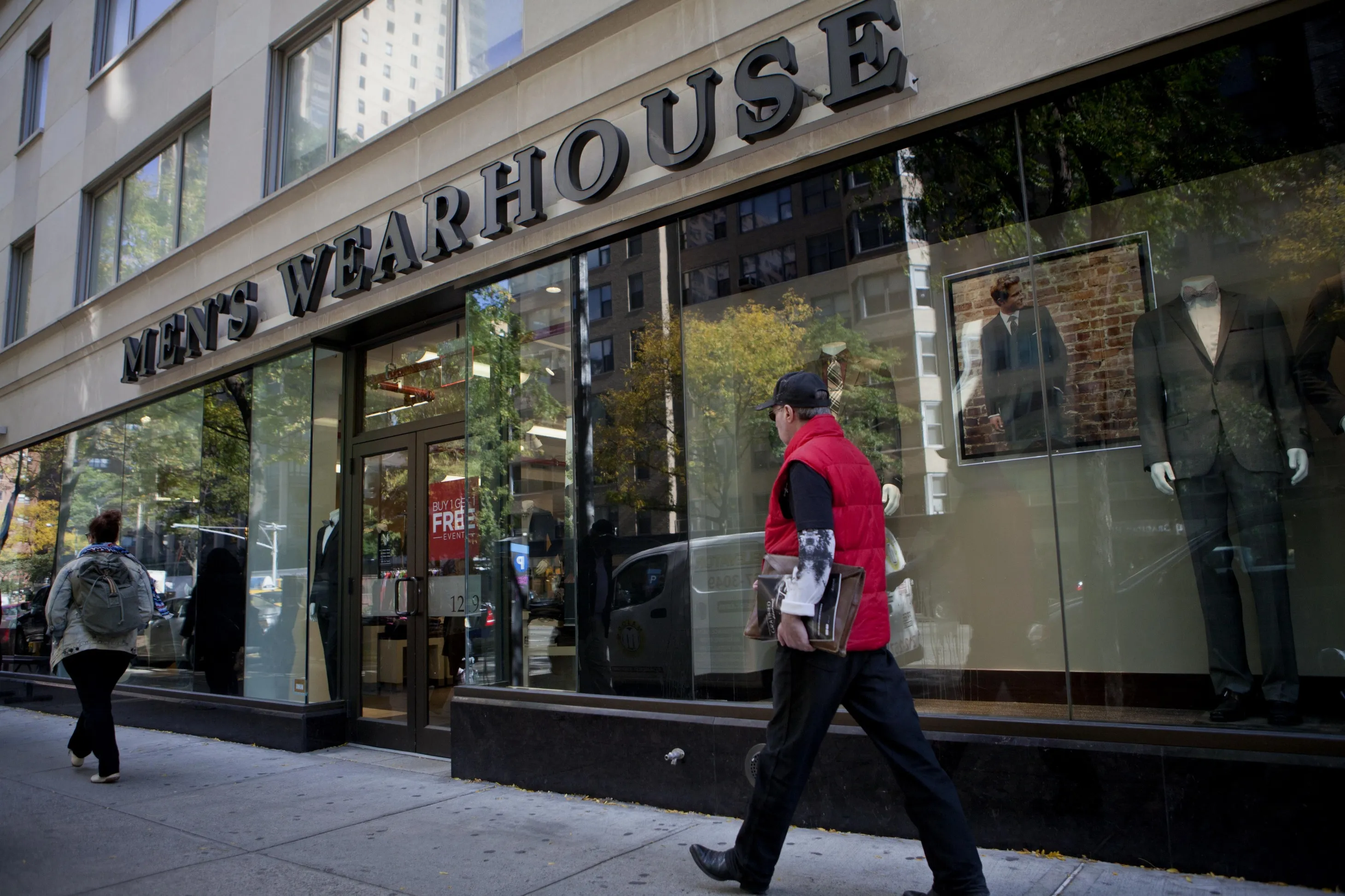 Pedestrians pass in front of a Men's Wearhouse store in New York.
