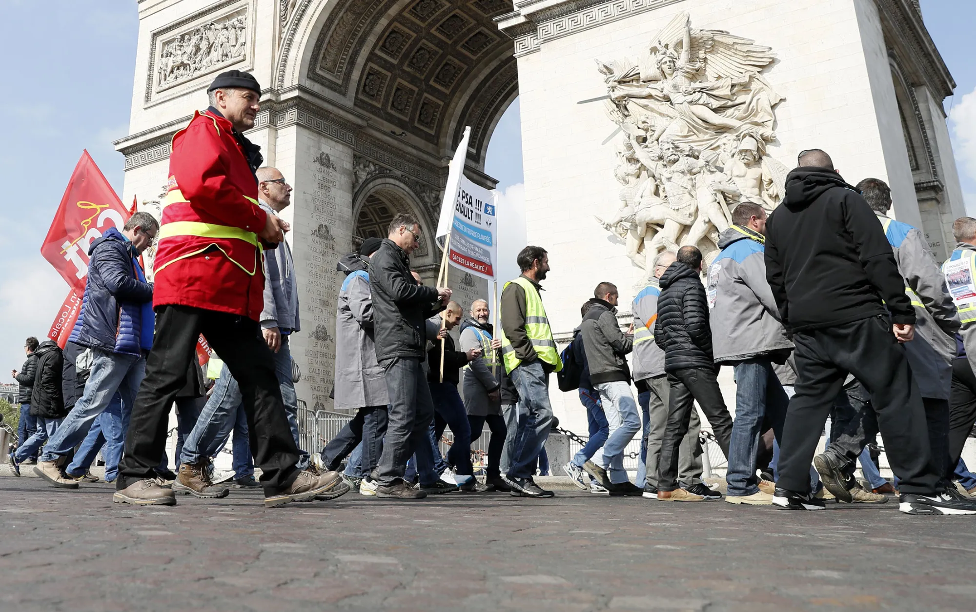 Workers march past the Arc de Triomphe during a demonstration against job cuts in Paris on April 19, 2017.
