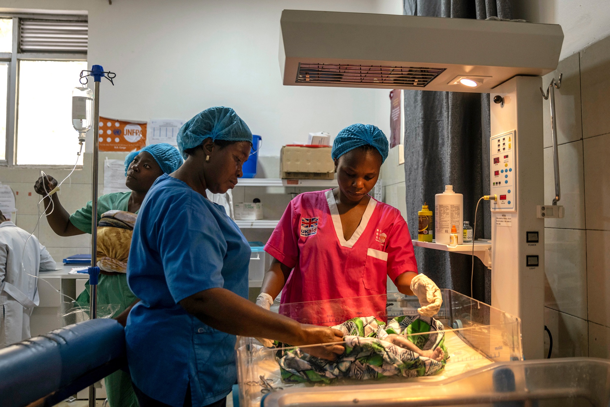 Healthcare workers in a maternity ward in Goma, Congo, caring for a newborn under a warming light.