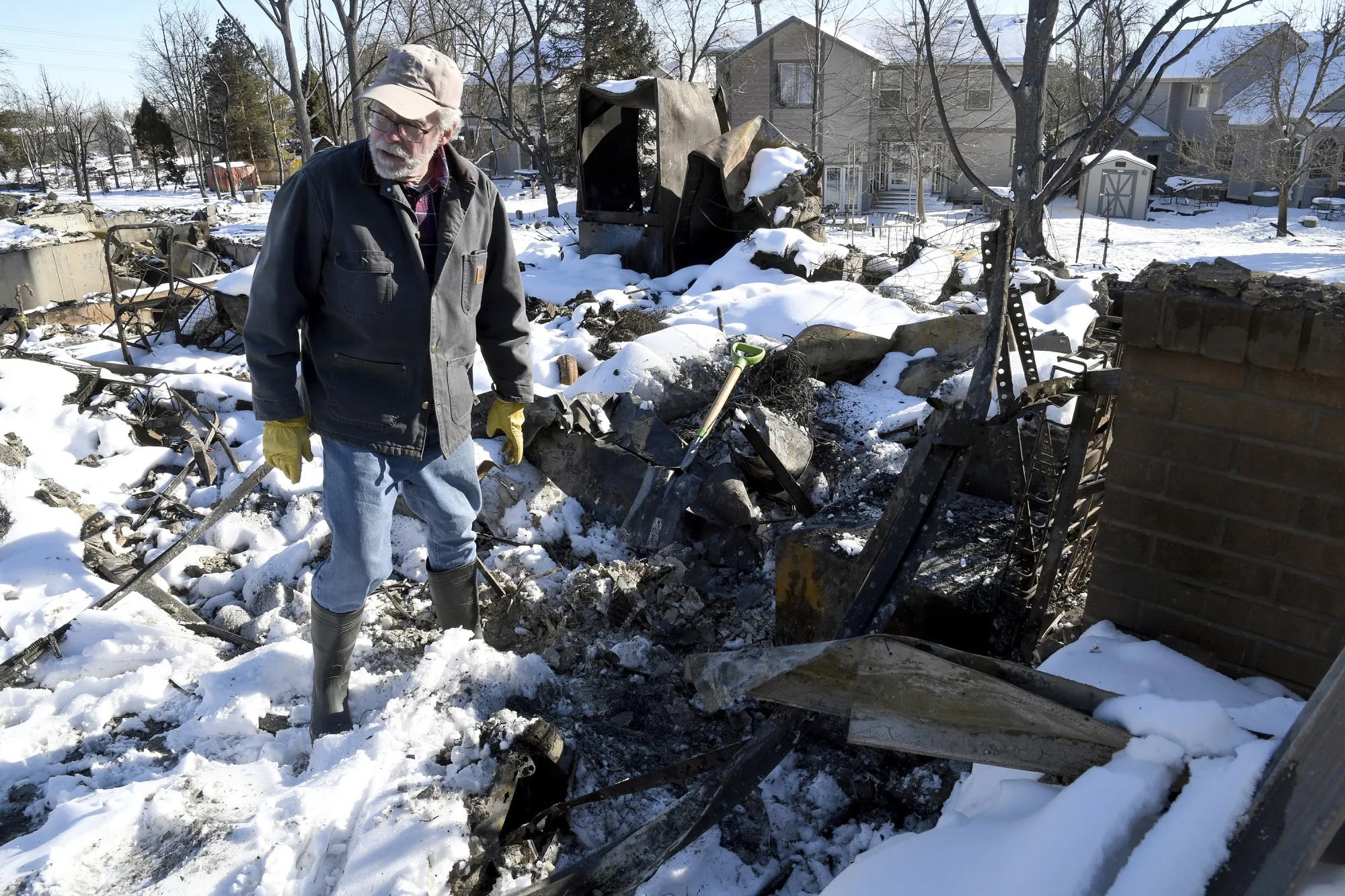 Rex Hickman sifts through the rubble of his burned home in Louisville, Colo., on Sunday, Jan. 2, 2022. Hickman, who had lived in the home with his wife for 23 years, found his safe, but little could be salvaged other than a few gold and silver coins. (AP Photo/Thomas Peipert)