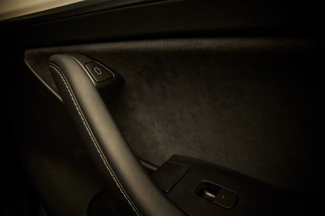 The interior of a 2023 Tesla Model Y. The top button opens the door. The manual release is between the button and the power window switch.