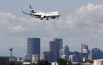 A WestJet Airlines Boeing 737 passes the downtown city skyline as it lands in Calgary.