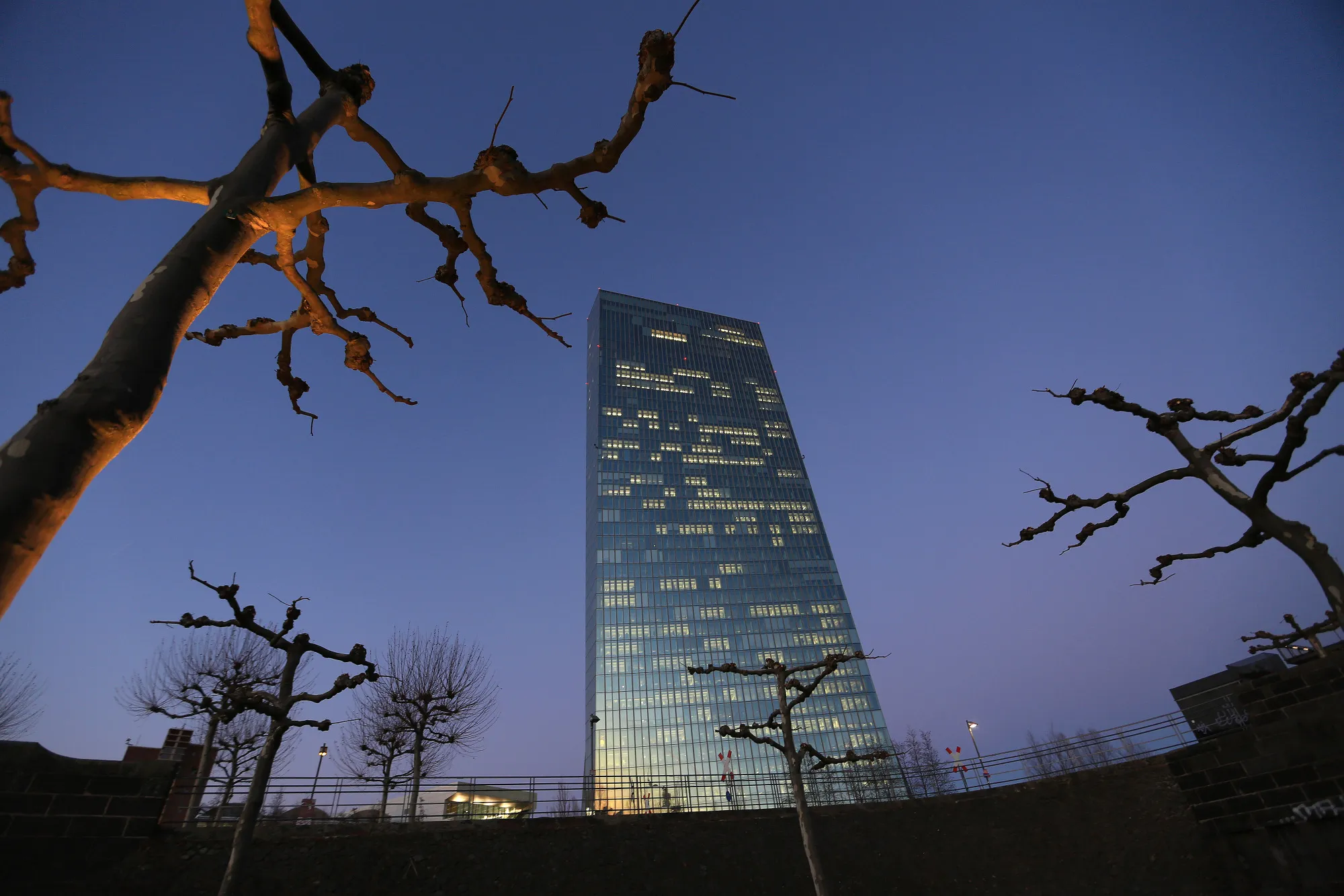 The European Central Bank skyscraper headquarters stand illuminated at dusk in Frankfurt, Germany.