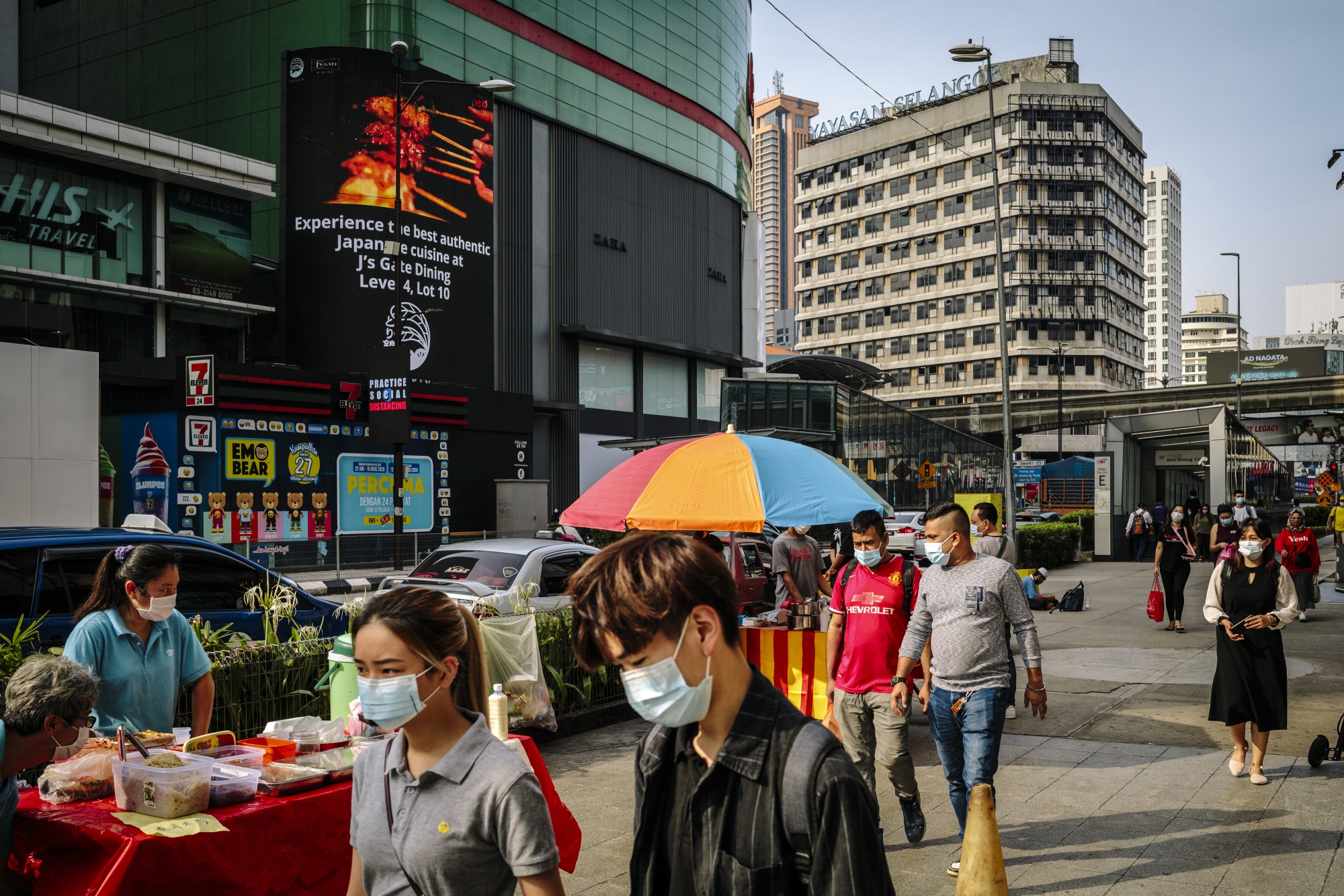 Pedestrians wearing protective masks walks past street vendors in Kuala Lumpur, on Sept. 28. Photographer Ian Teh/Bloomberg