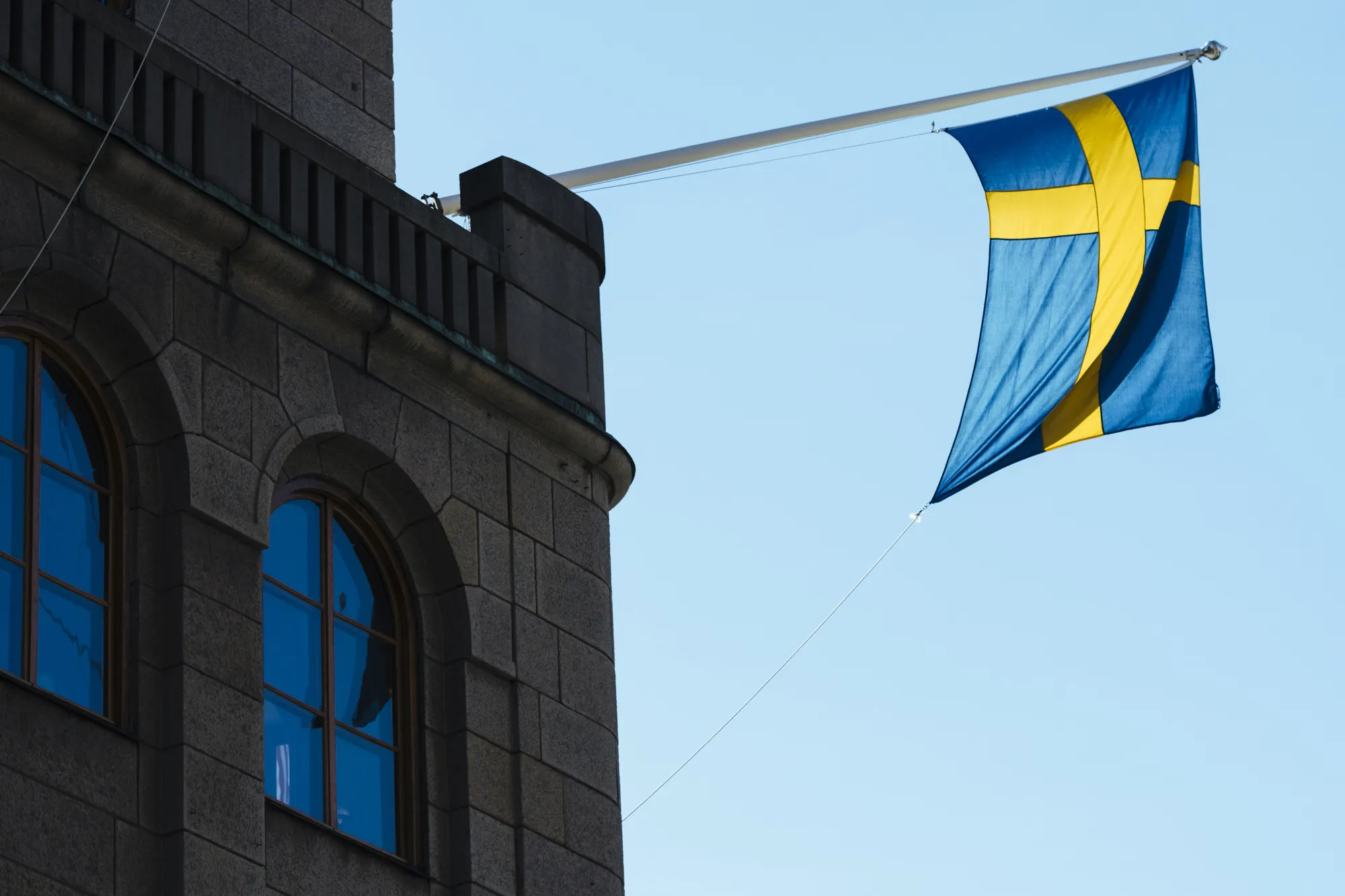 A national flag of Sweden flies from a commercial building in Stockholm.
