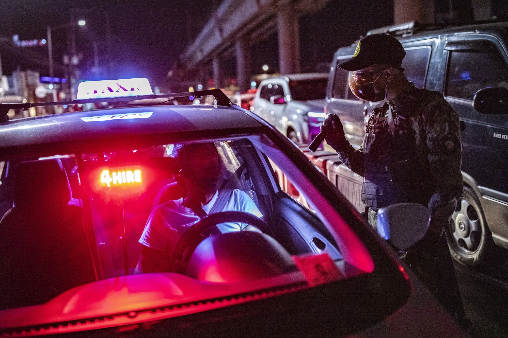 A police officer inspects motorists at a quarantine checkpoint as a strict quarantine is reimposed in Manila, on March 29.