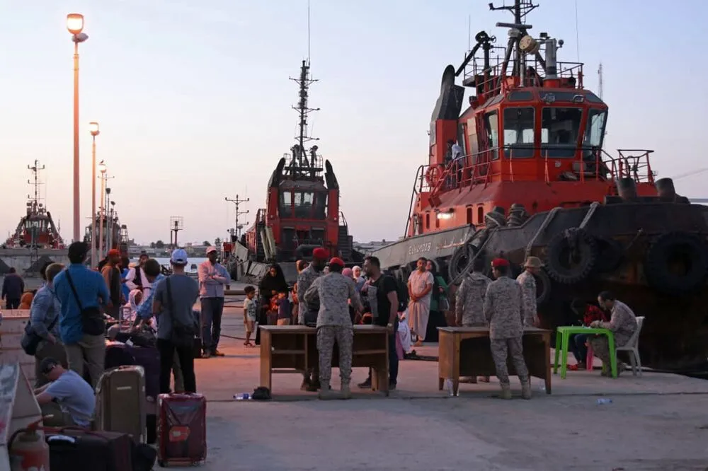People wait for evacuation on the dockside of Port Sudan on May 3, 2023.