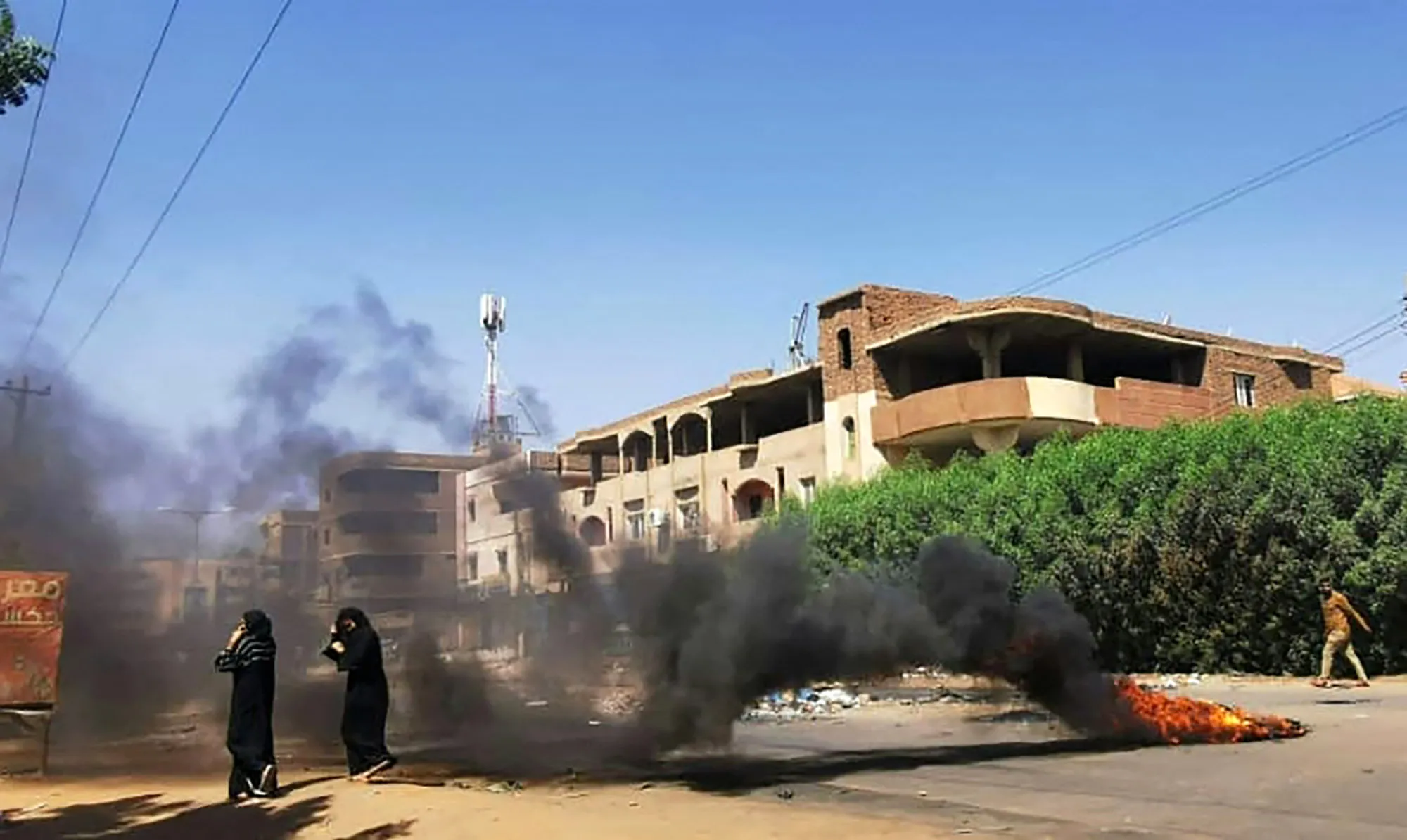 Sudanese women walk in front of tyres set ablaze by anti-coup demonstrators in Khartoum, on Nov. 7.