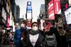 Pedestrians wearing protective masks walk through the Times Square neighborhood of New York, U.S., on Thursday, March 12, 2020.