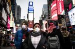 Pedestrians wearing protective masks walk through the Times Square neighborhood of New York, U.S., on Thursday, March 12, 2020.