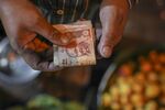 A man holds Indian twenty rupee banknotes at a shop in Mumbai, India.