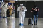 An airport security official in protective suit walks with a passenger at Shanghai Pudong Airport on March 26.