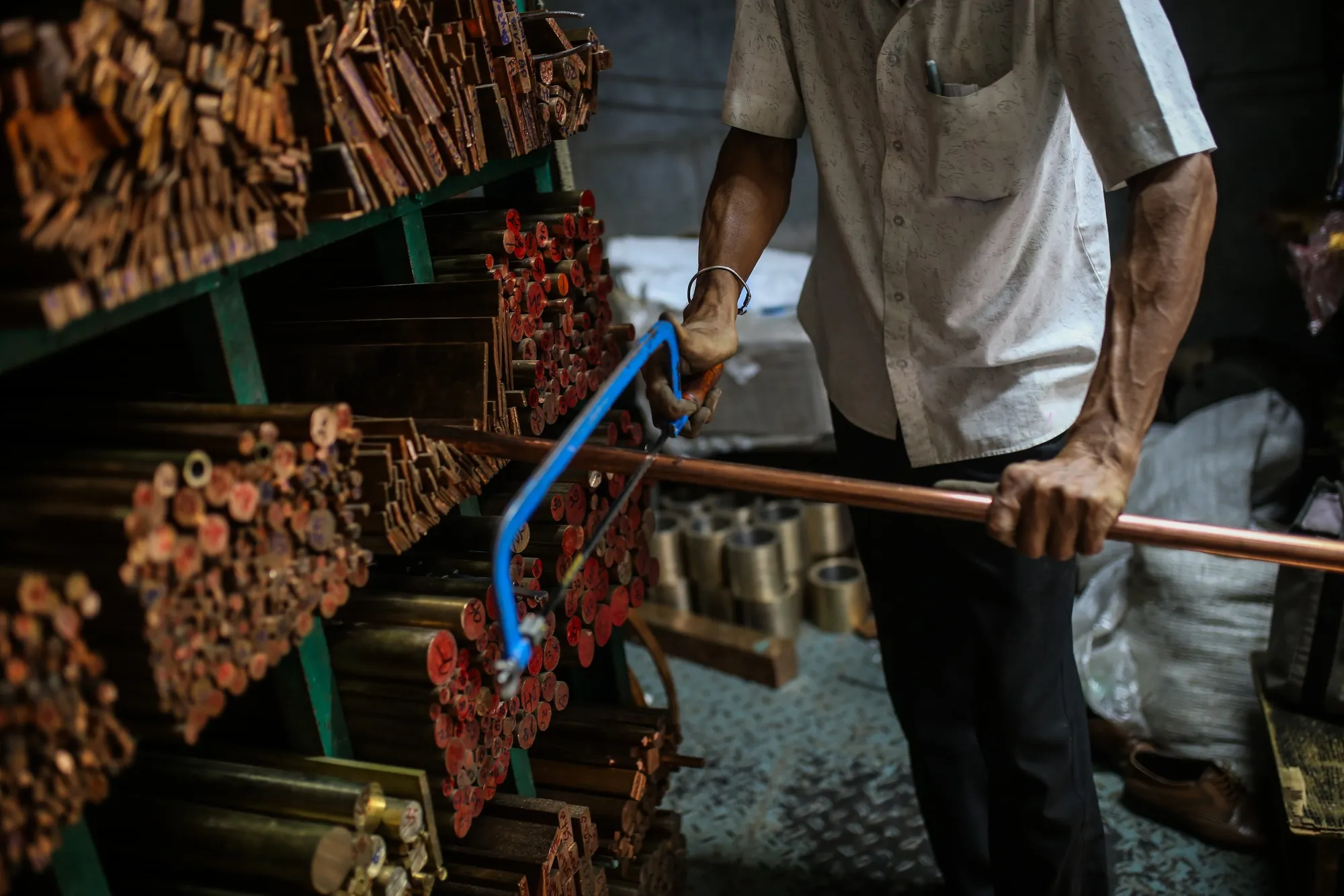 A worker cuts a copper pipe at a wholesale metal dealer in Mumbai, India.