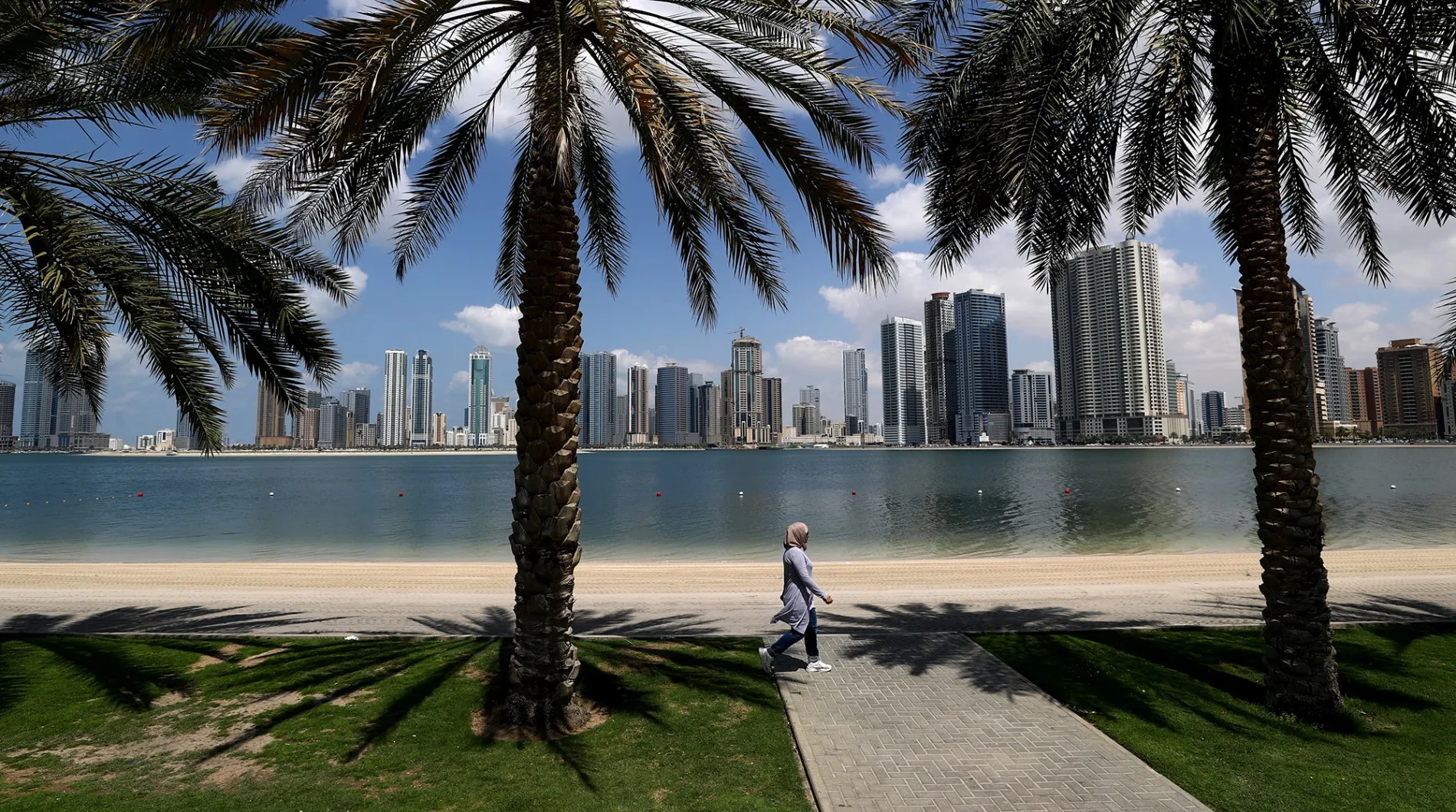 A woman walks along&nbsp;an empty beach in Sharjah, United Arab Emirates.