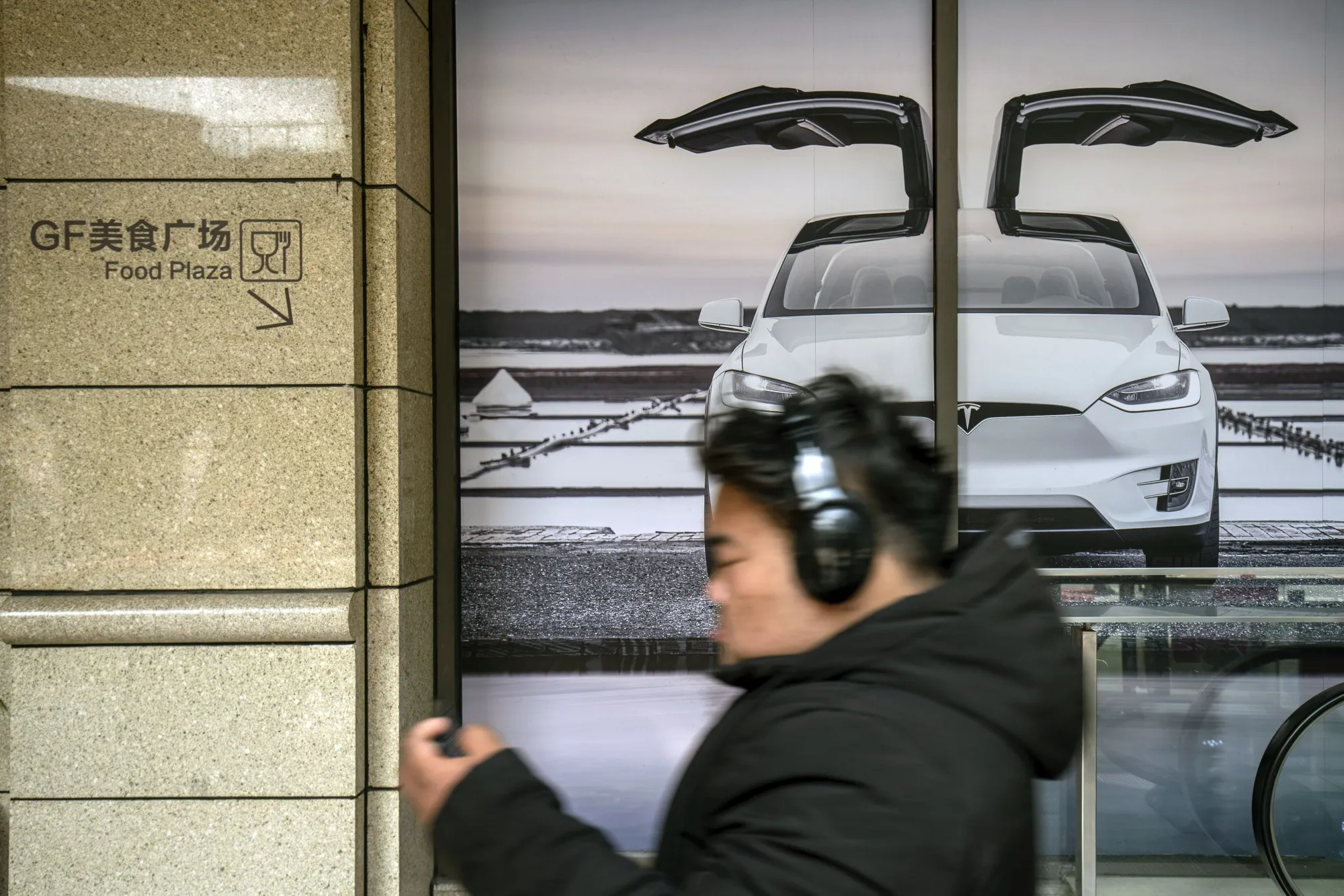 A shopper walks past the Tesla&nbsp;showroom at the Chamtime Plaza in Shanghai, China.