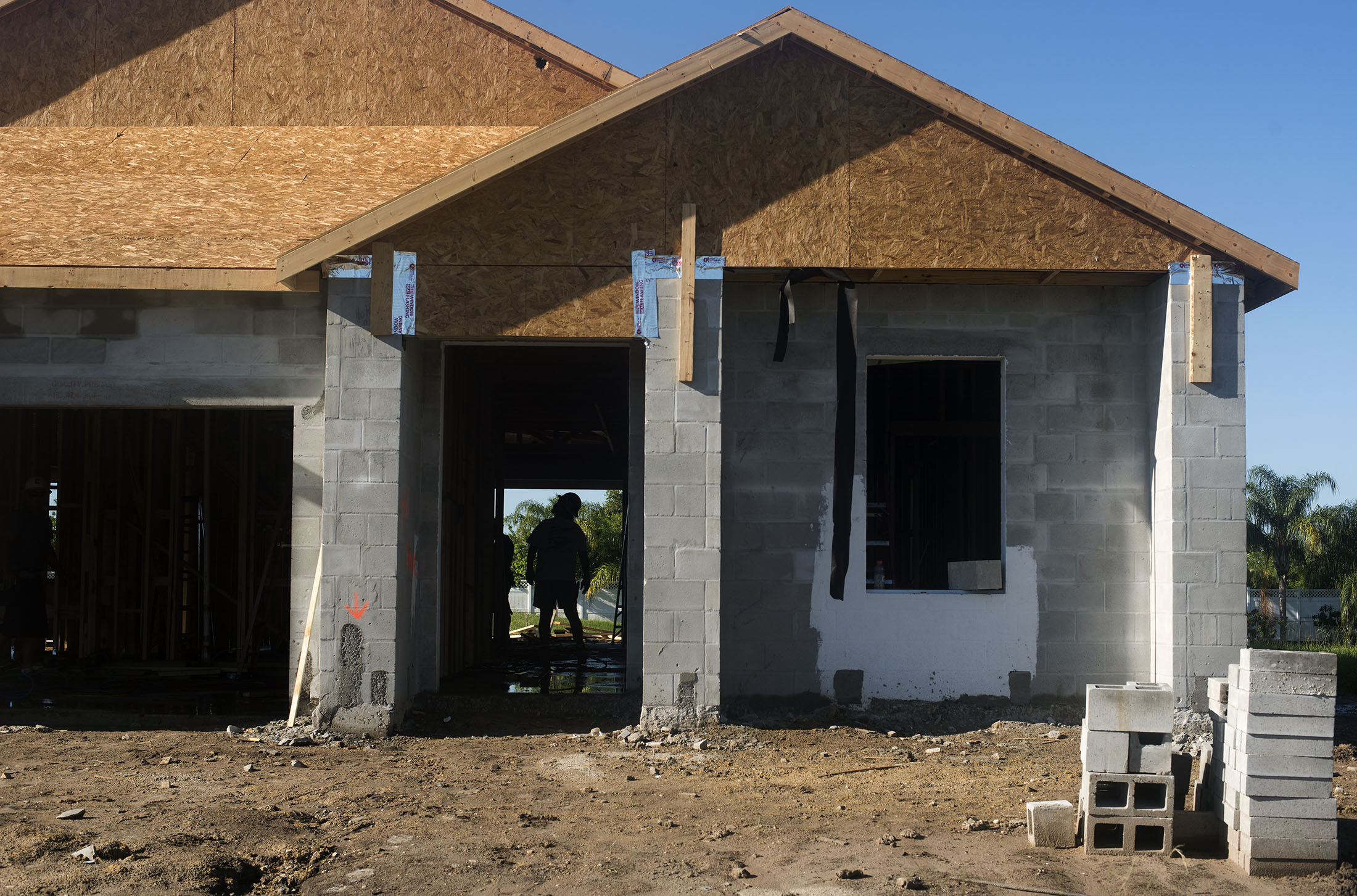The silhouette of a worker is seen inside a home under construction at the M/I Homes Inc. Bougainvillea Place housing development in Ellenton, Florida, U.S., on Thursday, July 6, 2017. The U.S. Census Bureau is scheduled to release housing starts figures on July 19.