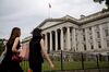 Pedestrians walk near the U.S. Treasury building in Washington, D.C., U.S., on Tuesday, Aug. 13, 2019. The Trump administration announced today it will delay until mid-December the 10% tariff on some Chinese products on many holiday-shopping lists, with the president acknowledging that the levies would have hurt consumers.