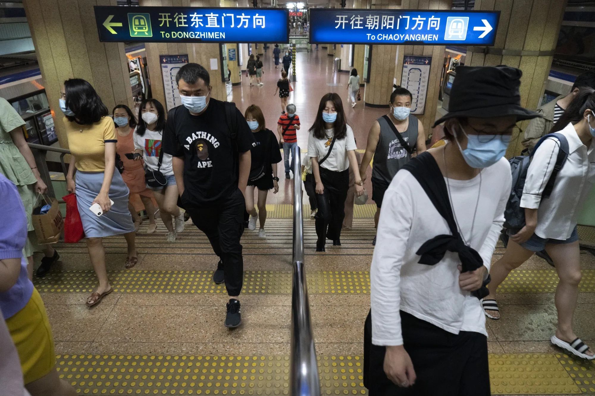 Commuters wearing protective masks ascend a flight of stairs at a subway station in Beijing.