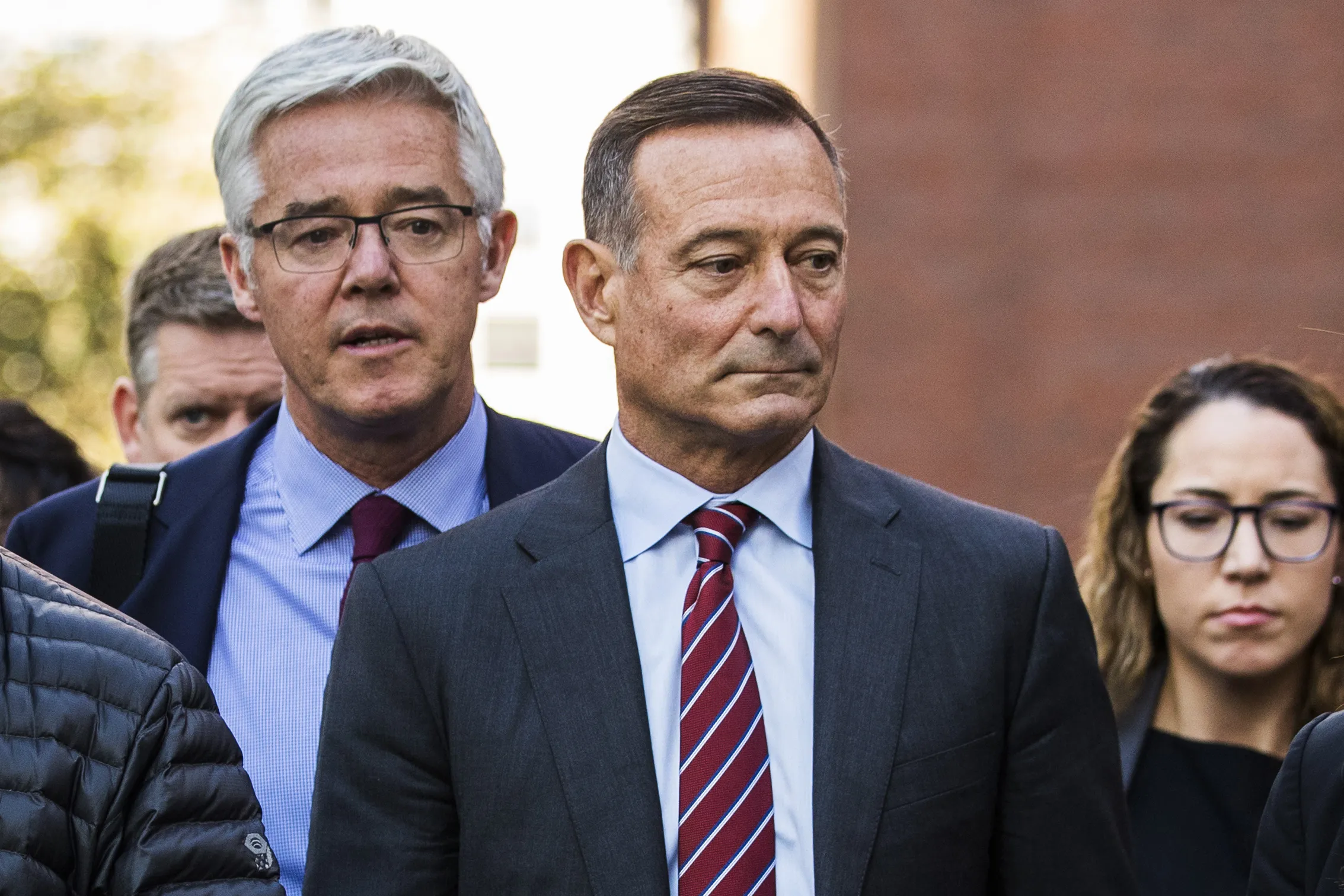 Douglas Hodge, center, exits federal court in Boston in 2019.
