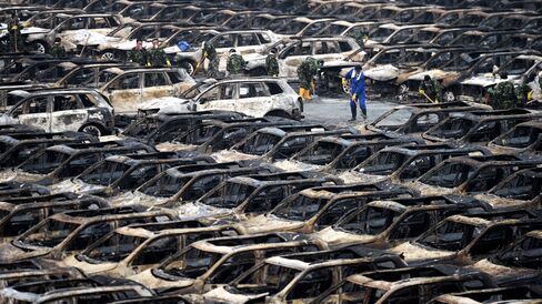 Rescue workers clear away debris next to rows of burnt cars in a parking lot near the site of the massive blasts in Tianjin, China.