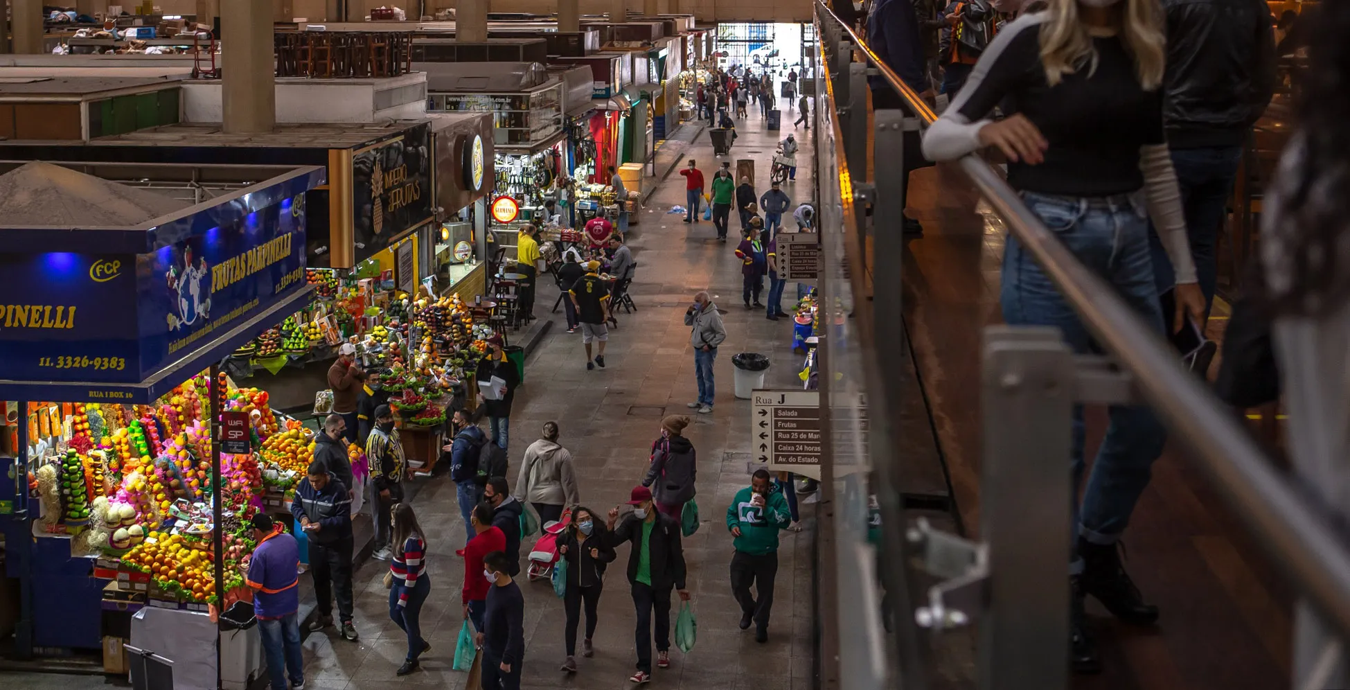 People wearing protective masks walk through a market in Sao Paulo.